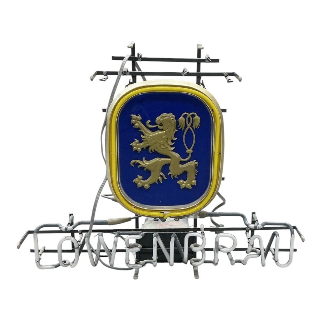 Vintage Löwenbräu Neon Beer Sign: Vintage Löwenbräu neon advertising sign featuring the brewery’s distinctive blue and yellow crest with a raised golden lion emblem. White neon tubing forms the Löwenbräu name