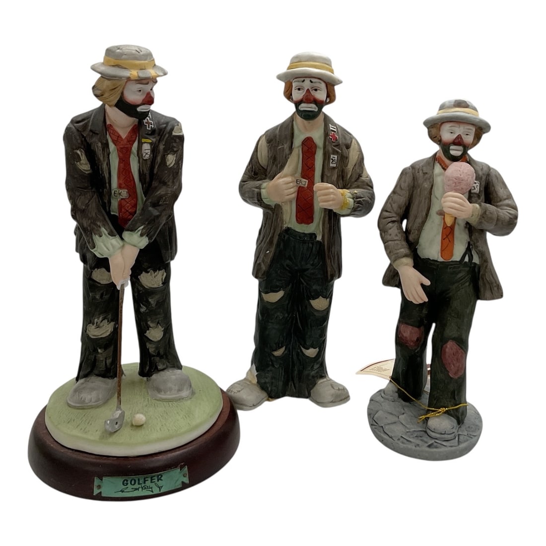 Emmett Kelly Jr. Clown Figurines by Flambro, Group of Three: Vintage group of three Emmett Kelly Jr. collectible clown figurines depicting the artist's familiar sad-faced hobo clown character in assorted poses. The group includes a golfer figure posed with 