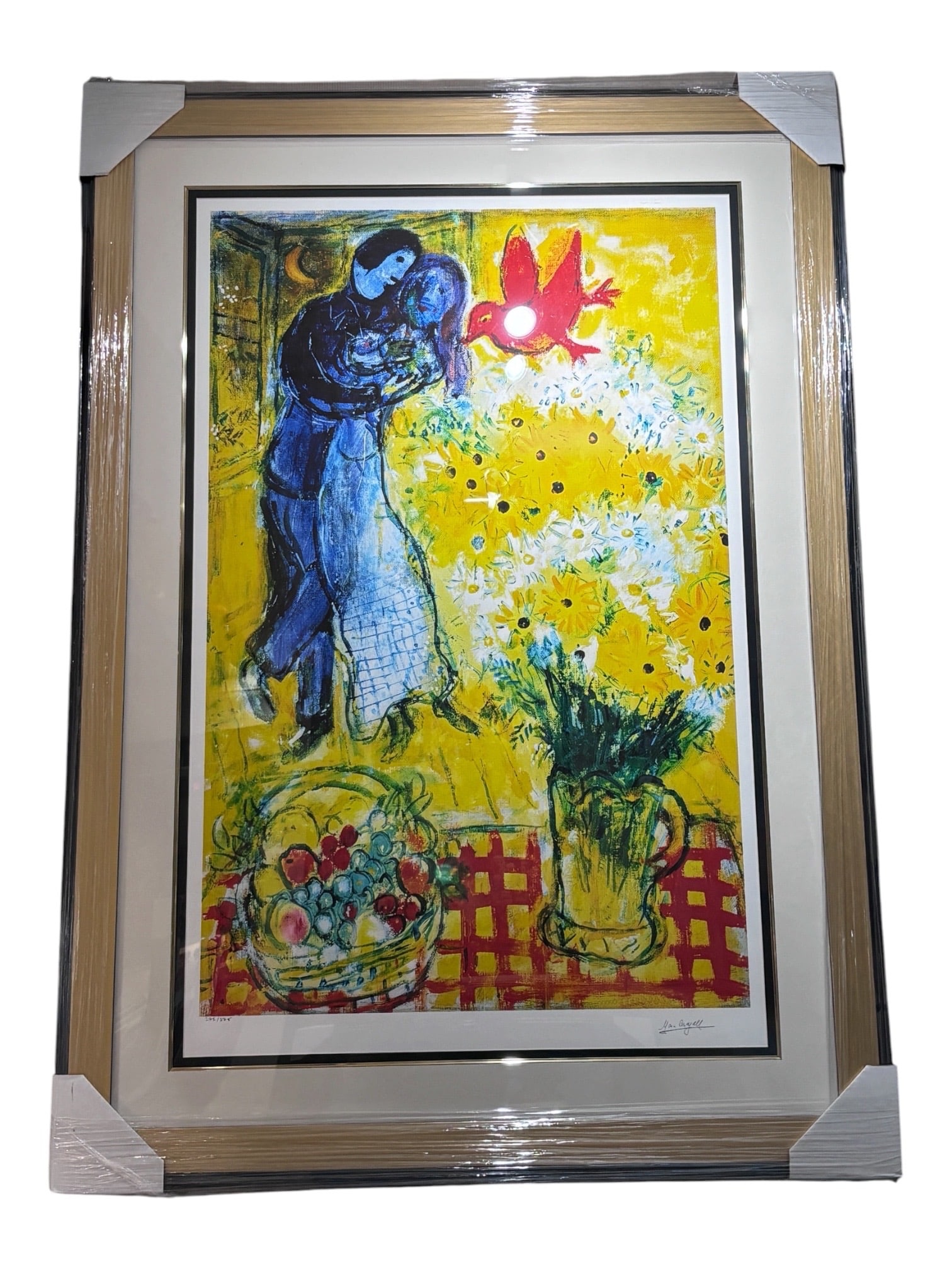 The Fiances with Bouquet (Les Fiances au Bouquet) by Marc Chagall (French/Russian, 1887-1985): A color lithograph after Marc Chagall depicting a pair of lovers embracing alongside a large vase of yellow flowers, a red bird, and a fruit basket atop a red checked tablecloth against a vibrant yell