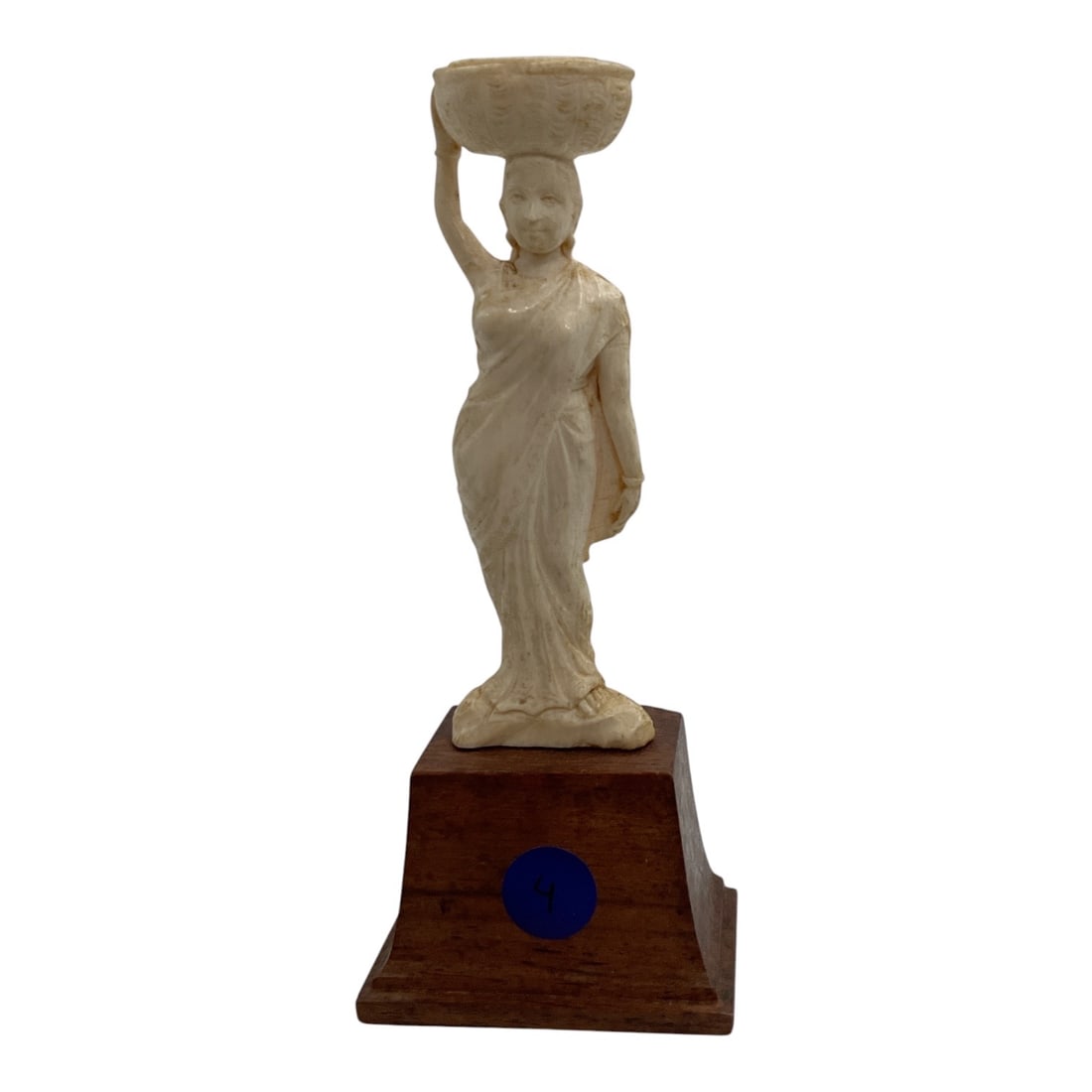Asian-Style Carved Female Figure Carrying Basket Sculpture: A carved Asian-style figural sculpture depicting a standing woman dressed in flowing traditional garments and balancing a large basket or vessel upon her head. The figure is posed with one arm raised 