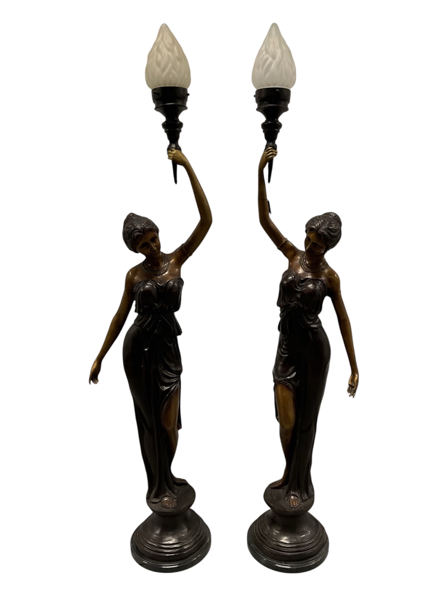 Pair of G. Mancini Bronze Figural Lady Floor Lamps: A striking pair of large bronze figural floor lamps, each depicting an elegantly posed woman in classical draped attire standing upon a tiered circular base. Each figure raises one arm overhead to sup