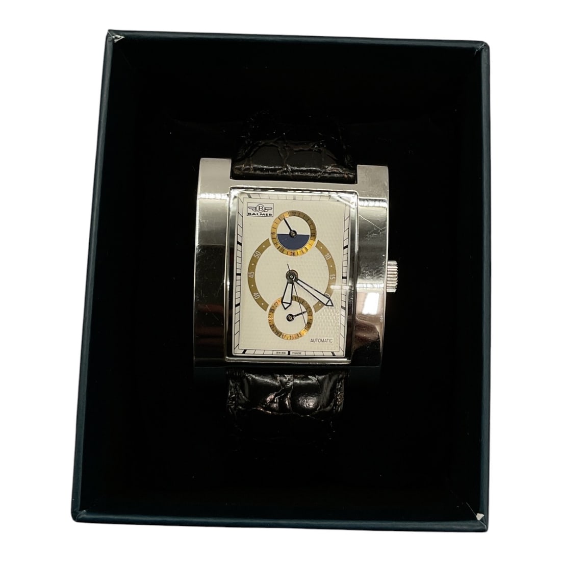 Brand New Balmer Rectangular Dual-Time Men's Wristwatch: A Balmer men's wrist watch featuring a wide rectangular stainless steel case housing a silver-tone and off-white dial with gold-accented sub-dials and blue complication displays. The timepiece is 