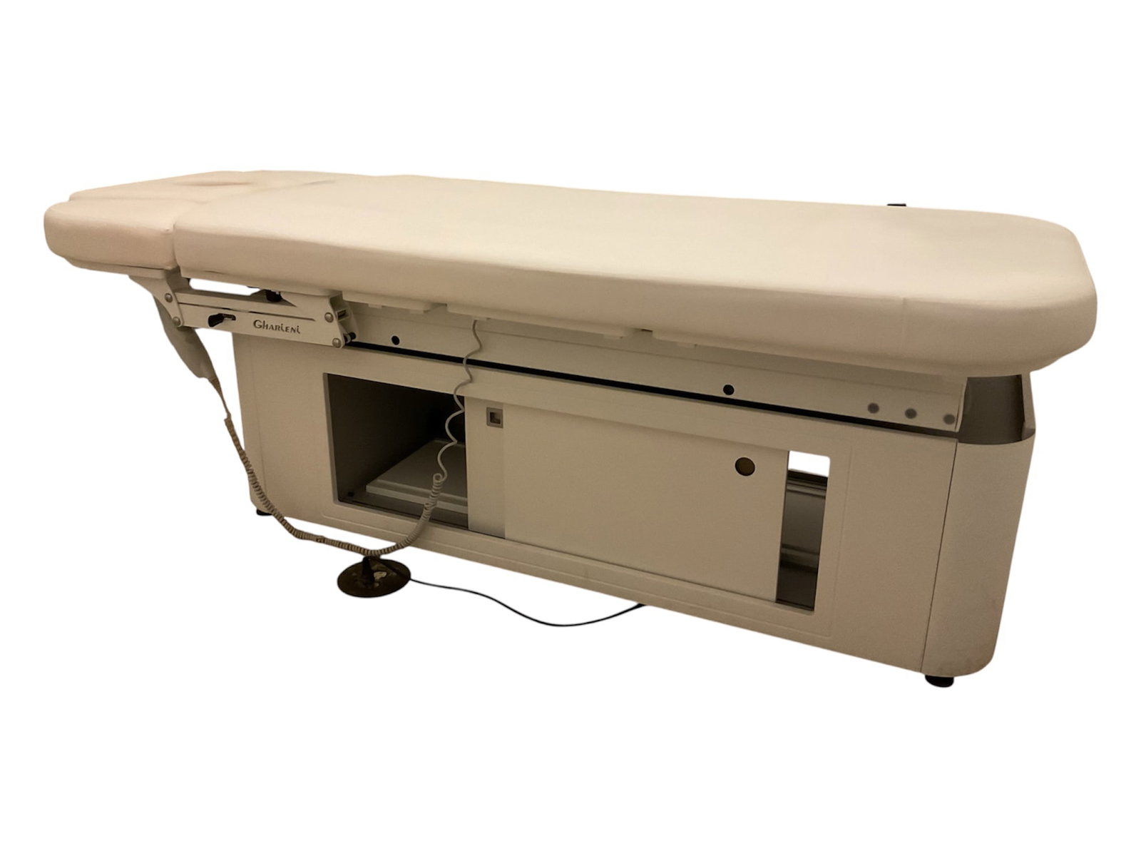 Gharieni Electric Spa Treatment Massage Table with Integrated Storage: A professional electric spa and wellness treatment table by Gharieni, featuring cream-colored padded upholstery with a segmented, articulated design for adjustable treatment positioning. The head sect