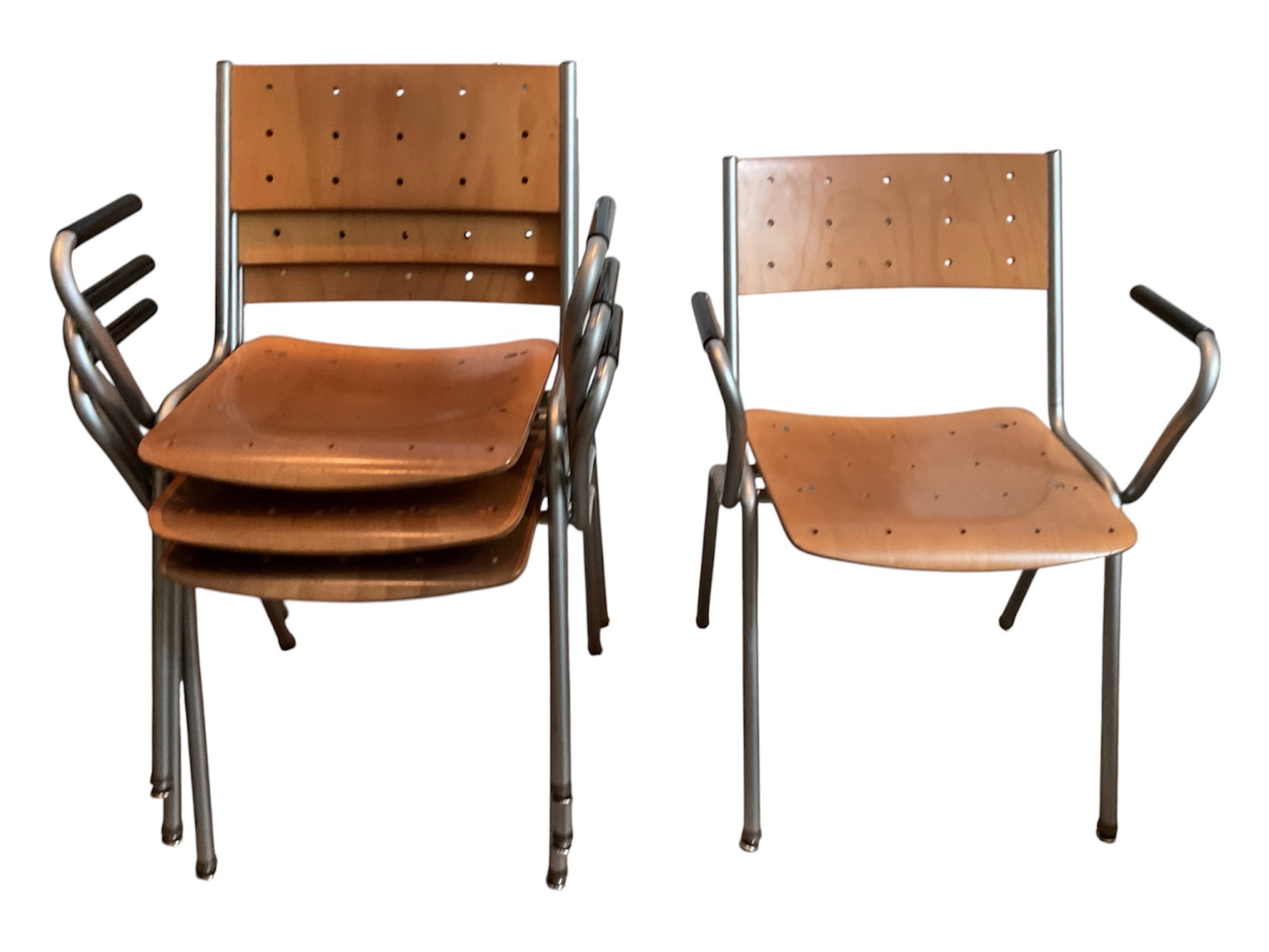 Set of Four Modern Perforated Wood Metal Armchairs: A set of four modern stacking armchairs featuring molded wood seats and curved backrests with distinctive geometric perforated detailing. Each chair is supported by a tubular silver-tone metal frame w