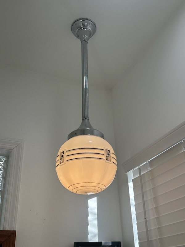 Art Deco Style Pendant Ceiling Light with Chrome Hardware and Ribbed Glass Shade: This ceiling-mounted pendant light features a rounded glass shade with horizontal ribbed detailing, inspired by classic Art Deco and machine-age design. The shade is paired with chrome-finished metal 