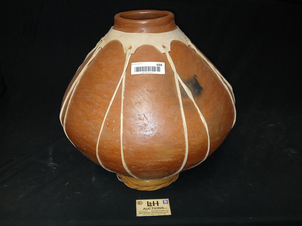 Mexican bulbous pottery vessel: Mexican bulbous pottery vessel, bound in leather, approx 17" tall with a 16" diameter at its widest point, on straw ring stand