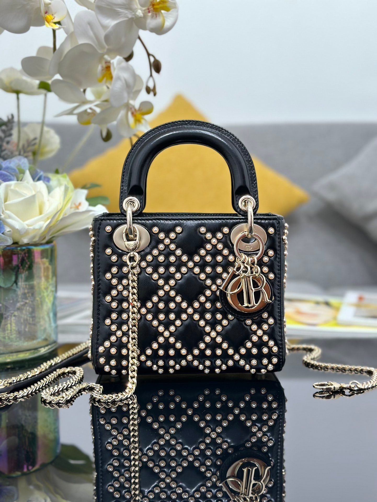Christian Dior: The Lady Dior features a three-section pearl-studded black design, lined with lambskin, crafted from waxed calfskin, and adorned with classic cannage beads for a unique and sophisticated look. A light