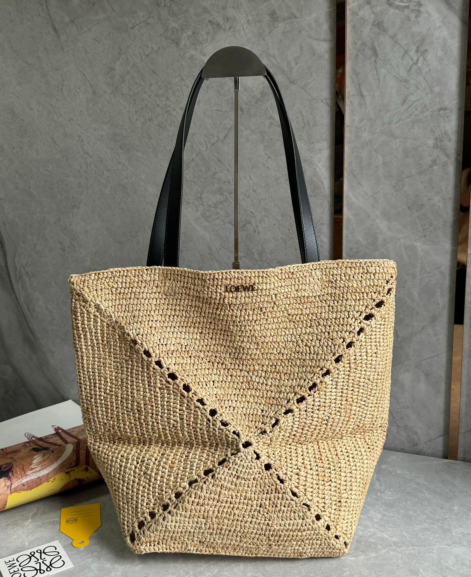 LOEWE Puzzle Fold tote: The LOEWE Puzzle Fold tote is a stylish woven bag. The brand uses creative ingenuity to create a soft and lightweight handbag, featuring cowhide leather handles and a gold-tone metal LOEWE logo. A per