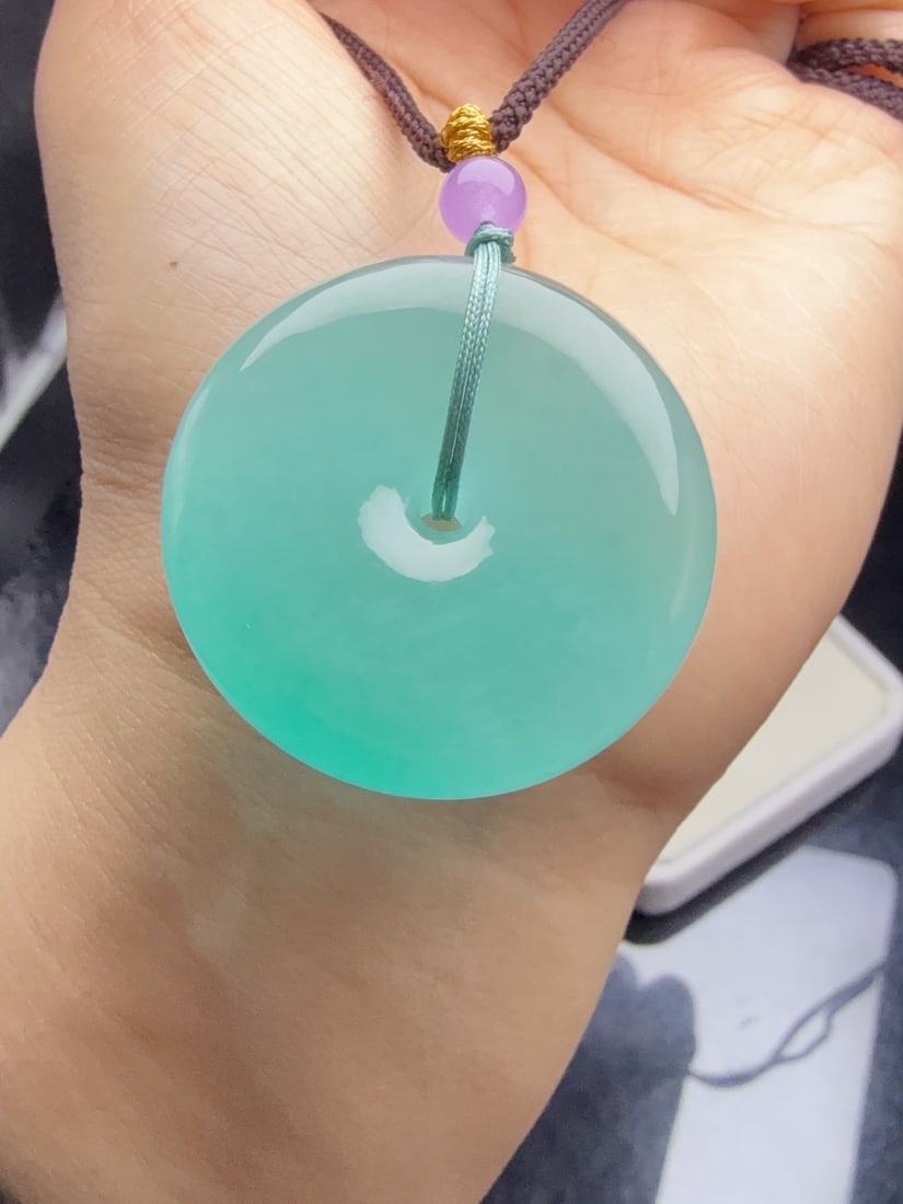 Jadeite icy blue "safety buckle": This jadeite "Peace Buckle" is of icy blue-green variety, with a lustrous and translucent appearance, exquisite three-dimensional design, thick and full texture, and flawless without any cracks. Prove