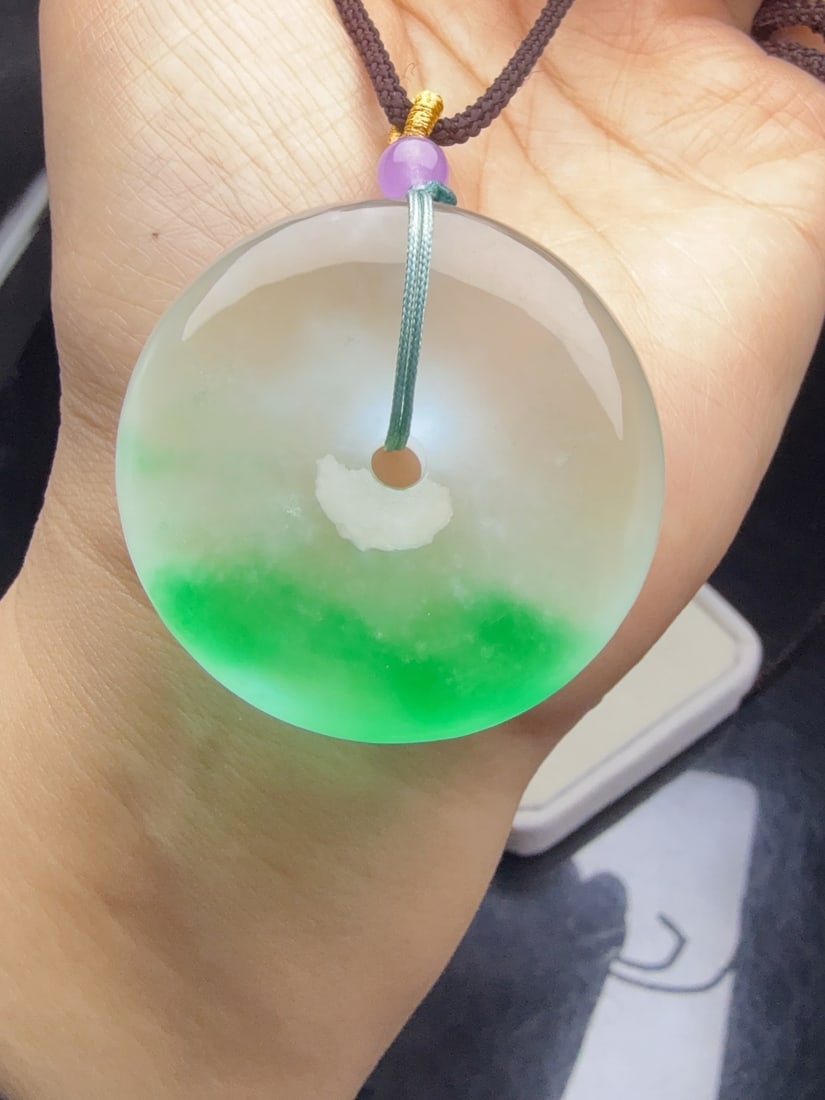 Jadeite "Peace Buckle" with Icy Green Surface: This jadeite "Peace Buckle" is of icy quality with floating green hues, exhibiting a lustrous and translucent appearance, exquisite three-dimensionality, a substantial and full shape, and is flawlessl