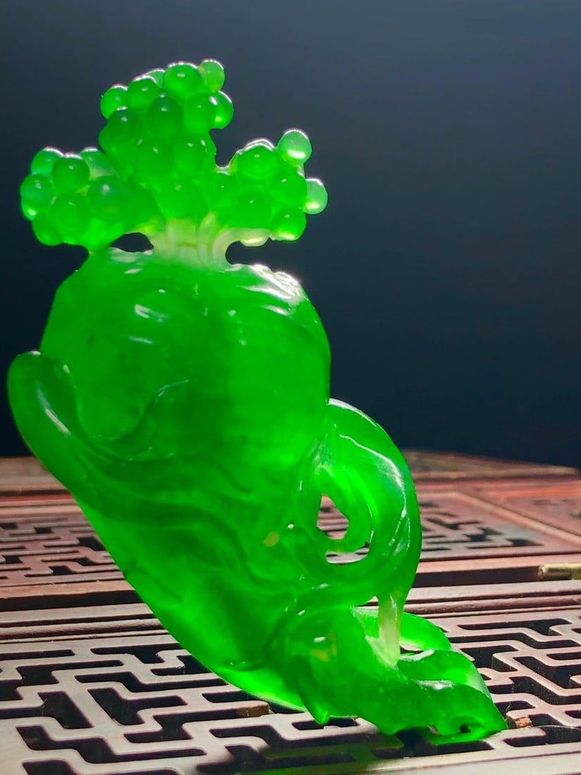 Imperial Green High-Ice Jadeite Human-Shaped Ruyi Ornament: This is a high-quality imperial green jadeite sculpture depicting a human figure with a ruyi (a traditional Chinese ornament symbolizing good fortune). It is carved from the same piece, made from supe