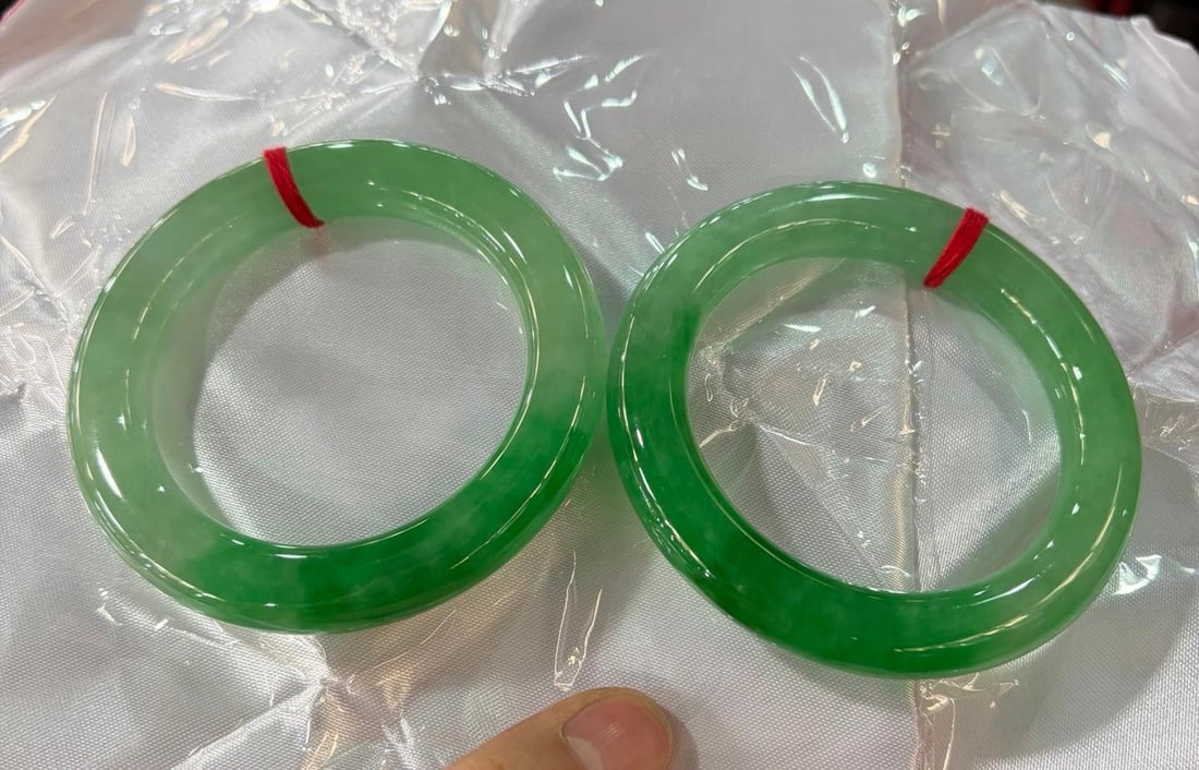 A pair of bean-green round jadeite bracelets: A pair of bean-green round jadeite bracelets Provenance:Private collection from a professor in The University of Edinburgh. Our cooperative logistics services provider expertly handles both domestic a