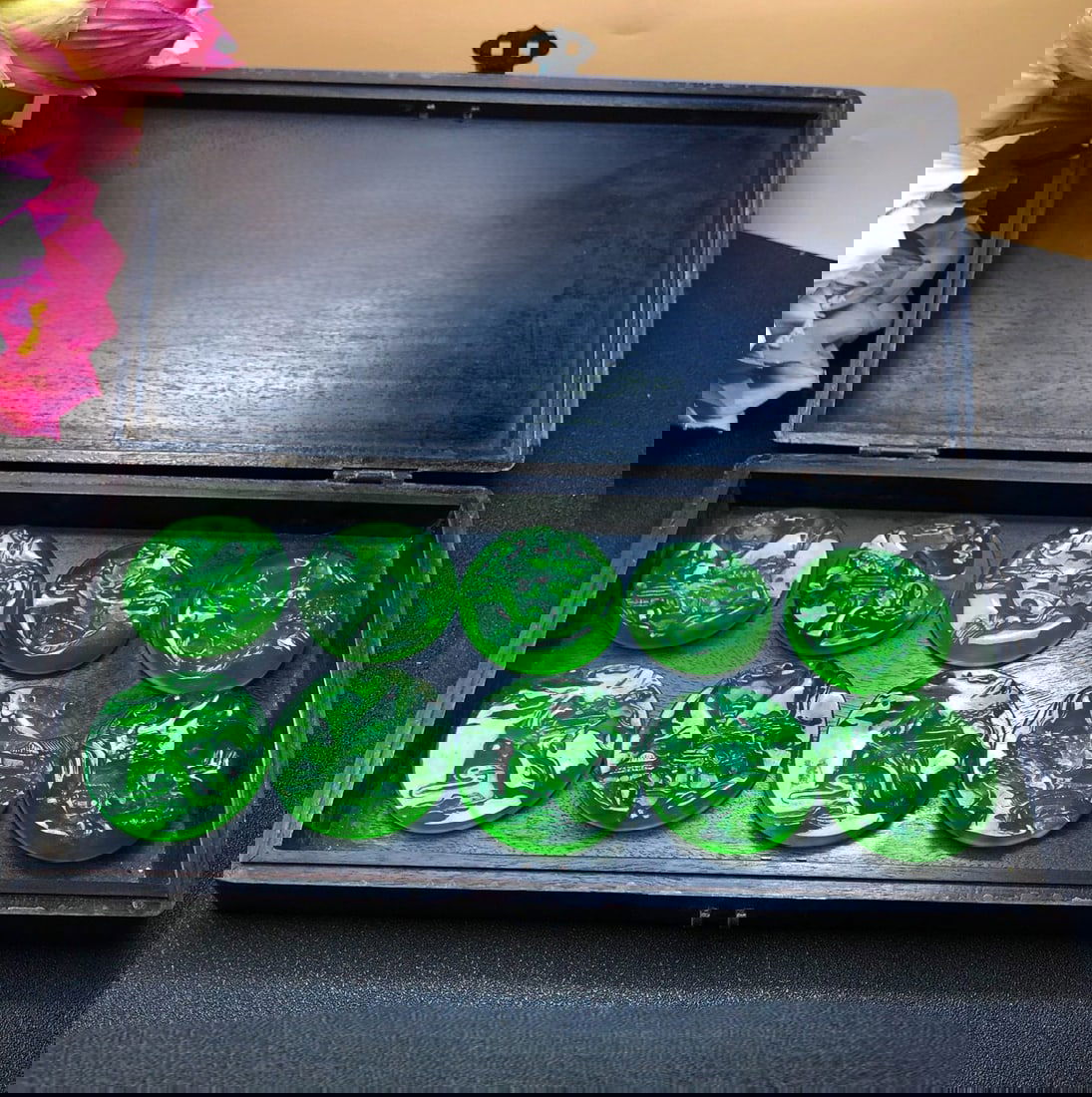 A round pendant carved with a landscape scene in imperial green jadeite relief, found inside a: Inside the rosewood box is a round pendant with a landscape relief carved from imperial green jadeite of high icy color. The material is of superior quality, icy and translucent, fully green and clear