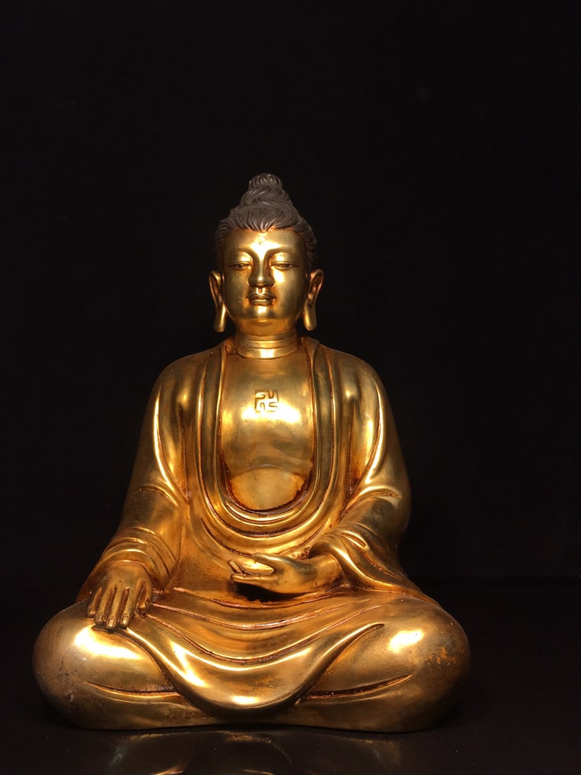 Golden Shakyamuni Buddha Statue: This gilded Shakyamuni Buddha statue is exquisitely crafted with a thick patina. It measures 21cm in width, 32cm in height, and 16cm in thickness, and weighs approximately 5000g. Provenance:Private co
