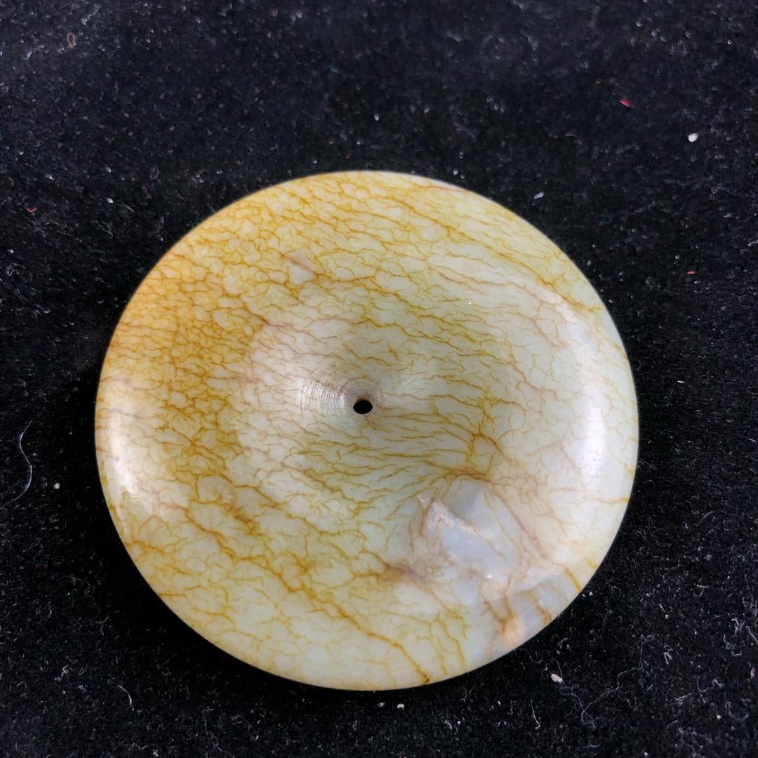 Hetian jade safety buckle: This Hetian jade safety buckle is well-preserved, with a smooth and oily texture. It has a diameter of 53.2mm and weighs 49g. Provenance:Private collection from a professor in University of Glasgow. O