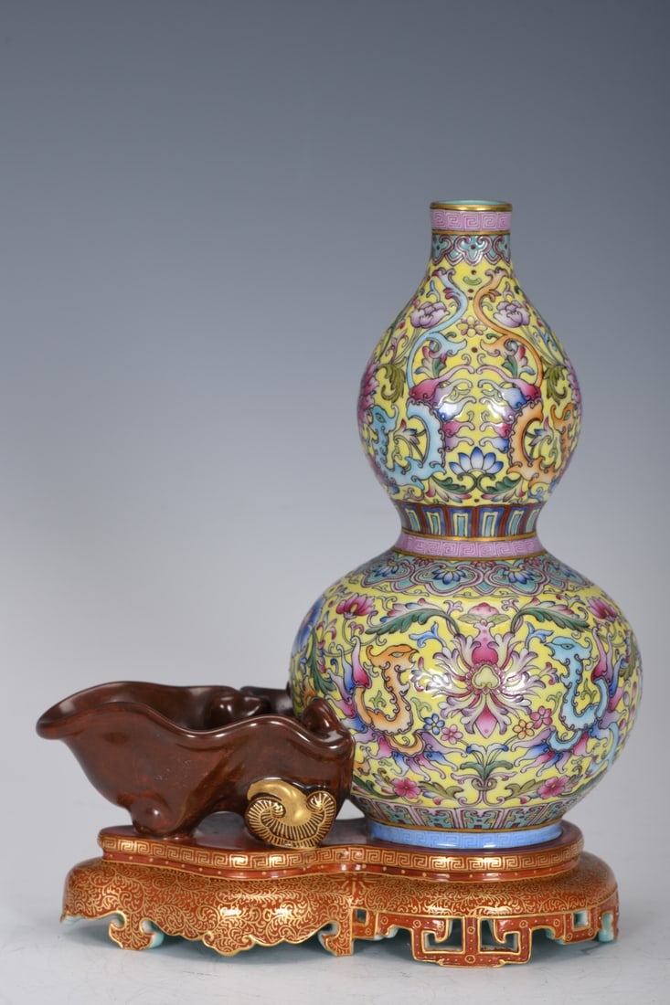 A Qing Dynasty Qianlong period enamel-painted gourd-shaped vase with a yellow ground, inscribed with: A Qing Dynasty, Qianlong period, enamel-painted gourd-shaped vase with a yellow ground, measuring 20.5 cm in height, 2.3 cm in mouth diameter, 17 cm in belly diameter, and 15.7 cm in base diameter. Pr