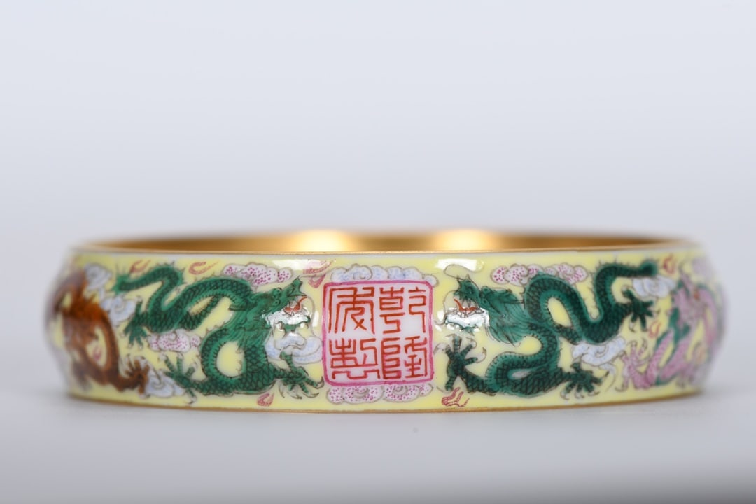 A Qing Dynasty Qianlong period enamel-painted yellow-ground nine-dragon bracelet: A Qing Dynasty Qianlong period enamel-painted yellow-ground nine-dragon bracelet, 1.7 cm thick, 7.5 cm outer diameter, and 6.5 cm inner diameter. Provenance:Private collection from a professor in Univ