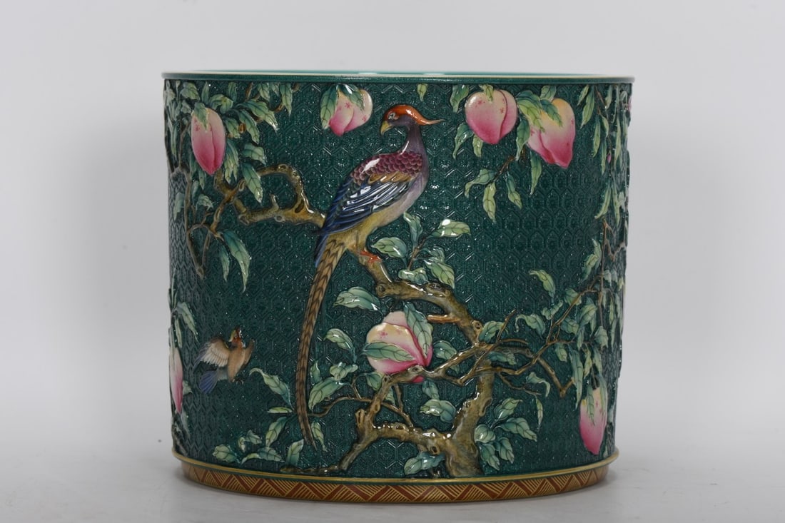 A large enamel-painted brush with a green ground and carved peaches, flowers, and birds, dating from: large enamel-painted brush with a green ground and carved peach blossoms and birds, dating from the Qianlong period of the Qing dynasty. It measures 15.6 cm in height, 18.2 cm in mouth diameter, and 1