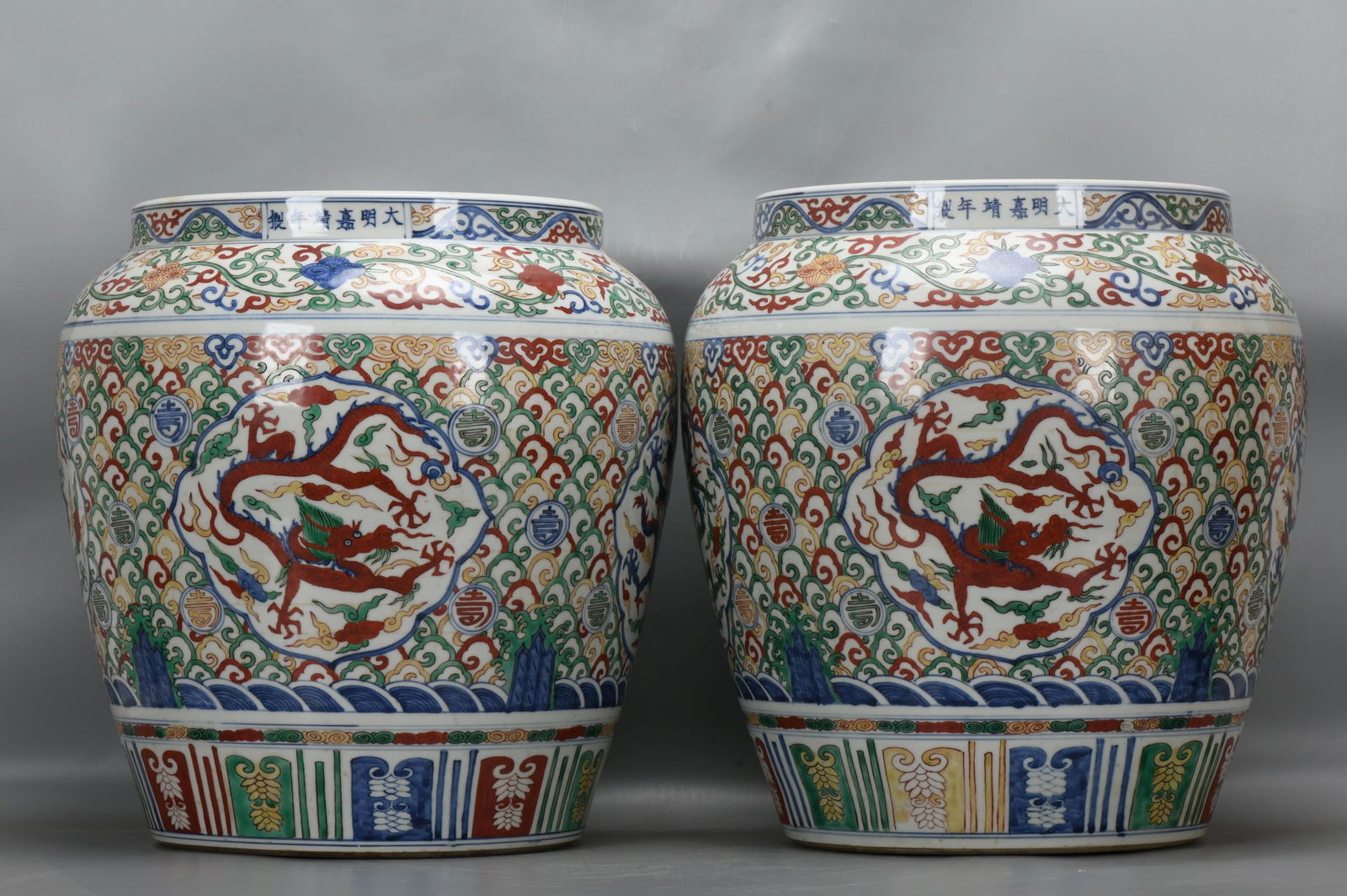 A pair of Ming Dynasty, Jiajing period, polychrome lotus scroll, longevity character, and dragon: A pair of Ming Dynasty, Jiajing period, polychrome jars with lotus scroll, longevity character, and dragon design, 41 cm high, 30.5 cm in mouth diameter, 40 cm in belly diameter, and 27 cm in base dia
