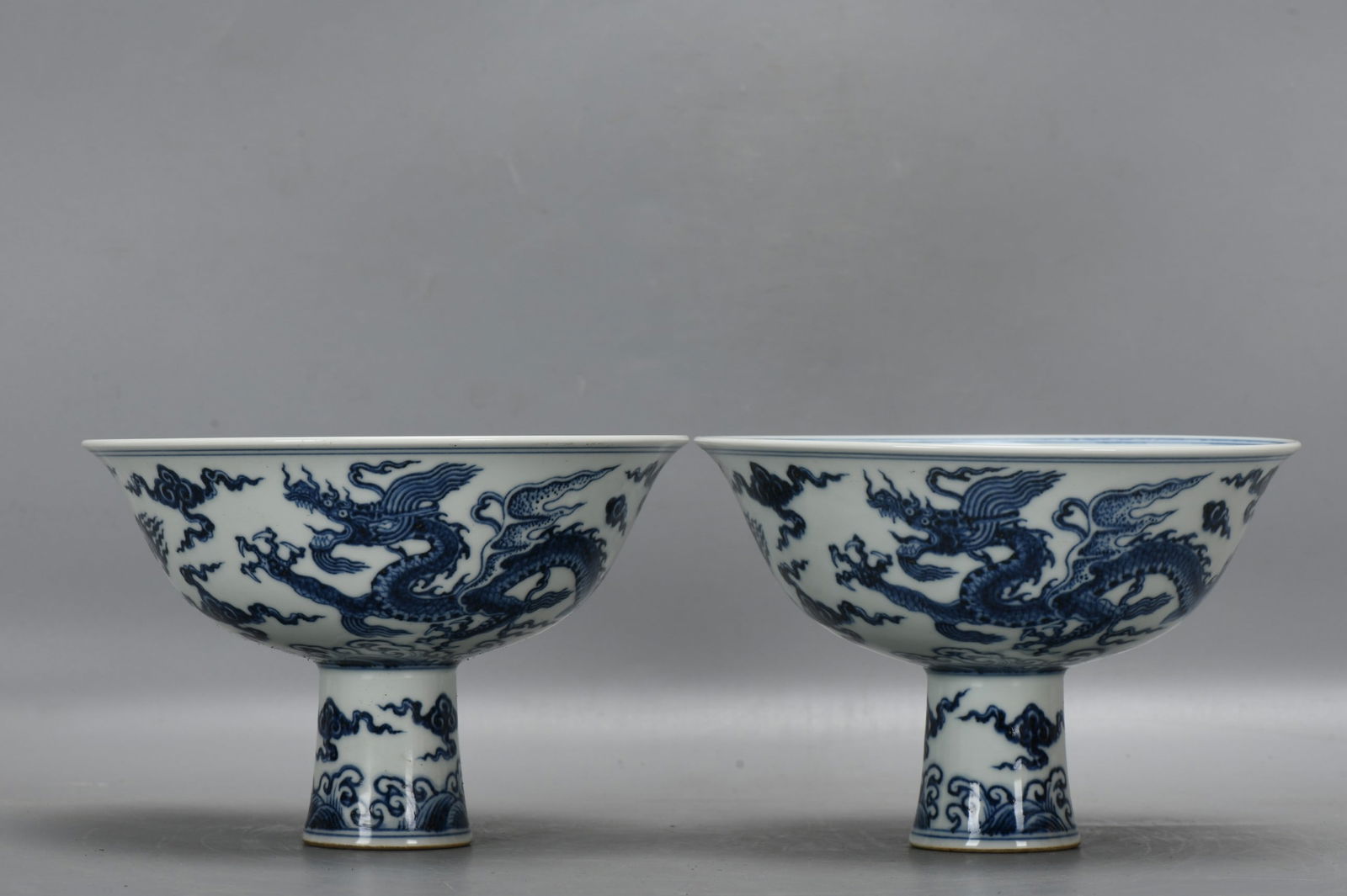 A pair of Ming Dynasty Xuande blue and white stem bowls with a design of flying dragons amidst (1 of 9)