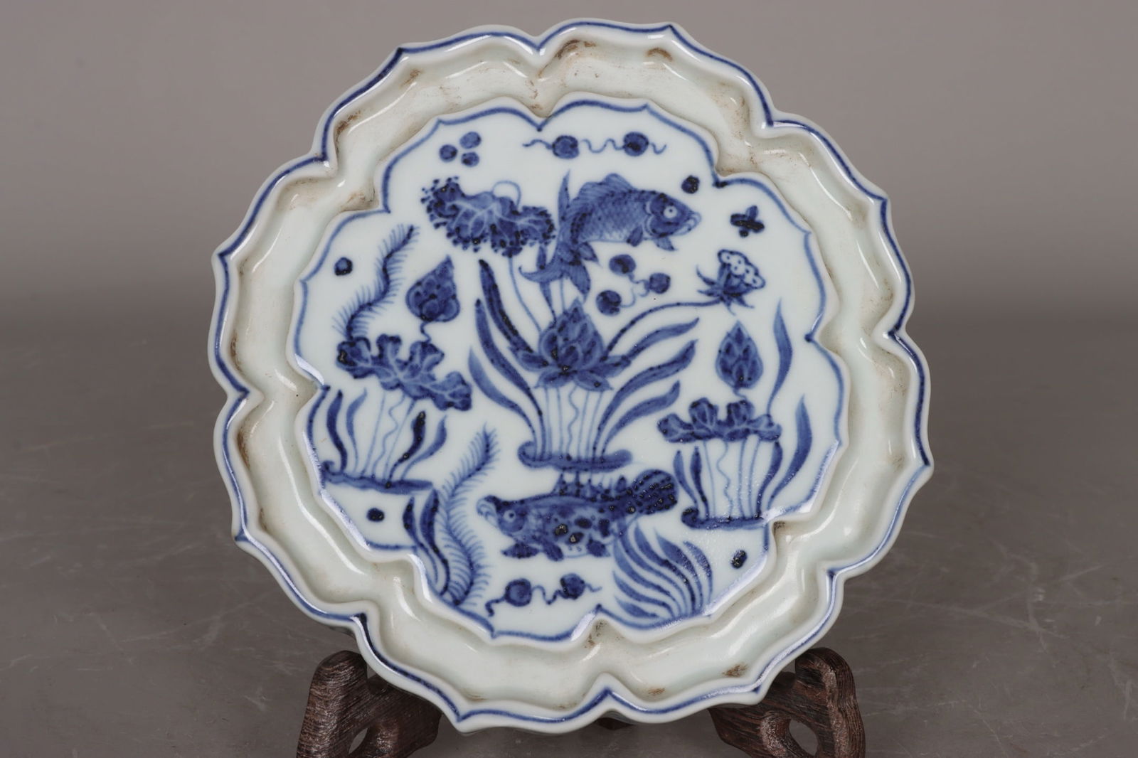 A Ming Dynasty Xuande period blue and white porcelain tea saucer with a fish and grass design.: A Ming Dynasty Xuande period blue and white porcelain tea saucer with a fish and grass design, 2.5 cm high and 15.2 cm in diameter. Provenance:From an old private collection in Cotswold, United Kingdo