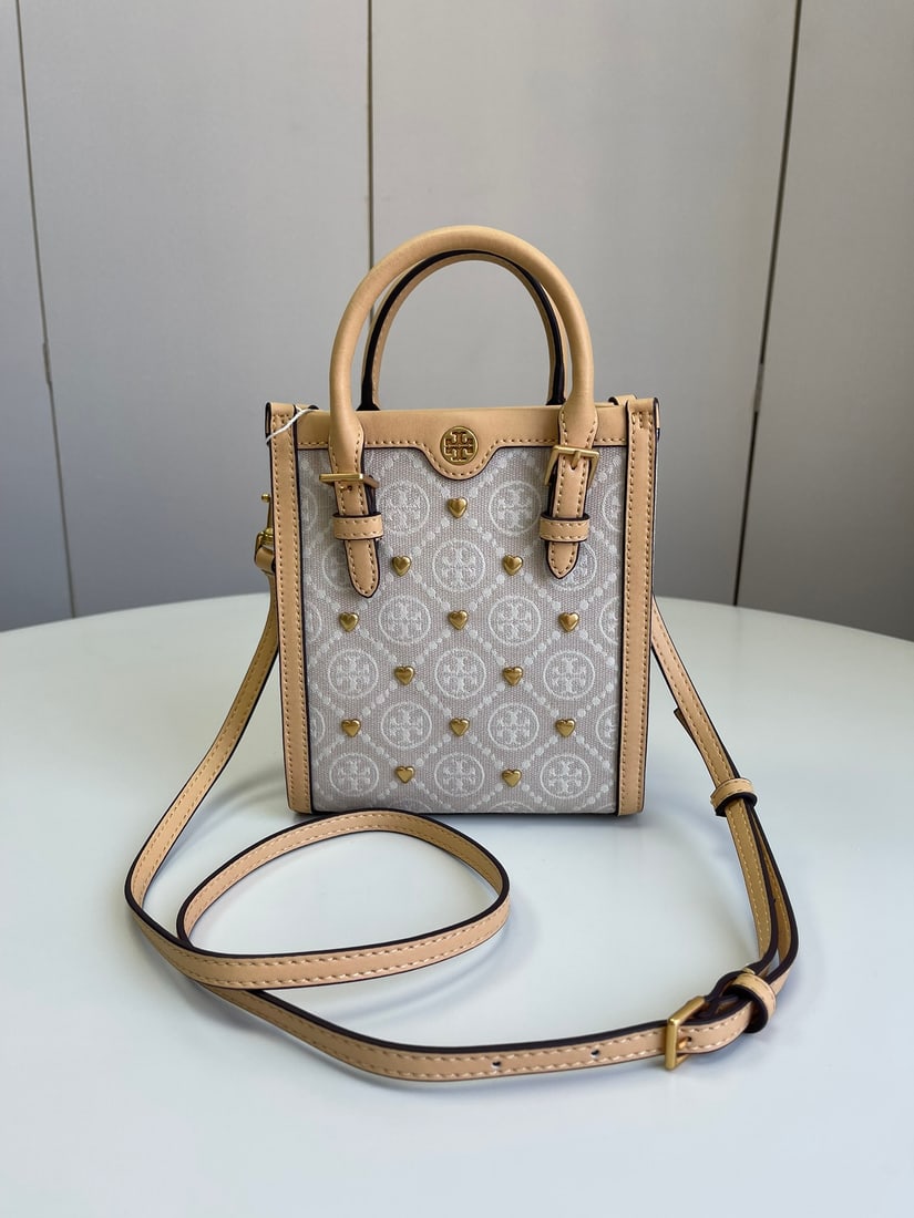 Tory Burch T MONOGRAM JACQUARD MINI NS TOTE: The Tory Burch T MONOGRAM JACQUARD MINI NS TOTE is a vertical, retro-style tote bag perfect for autumn/winter. The leather handles accentuate its compact yet structured shape, showcasing clever