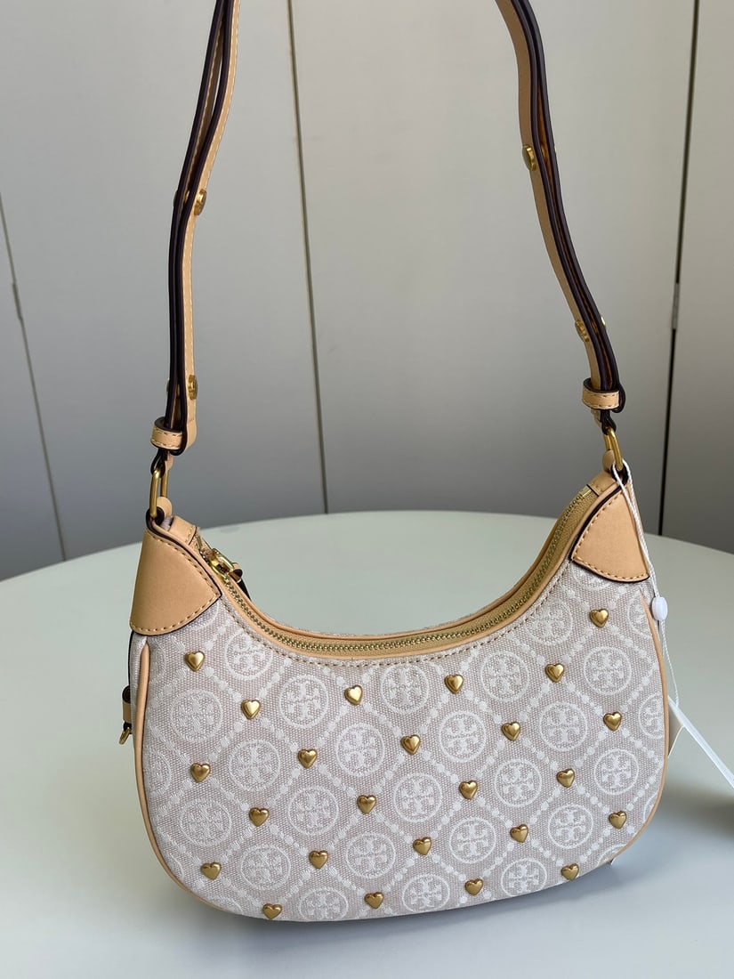 Tory Burch: The classic T Monogram pattern is crafted from jacquard fabric and trimmed with premium leather. A timeless piece, it exudes style. The T Monogram Crescent bag features soft suede leather trim and an