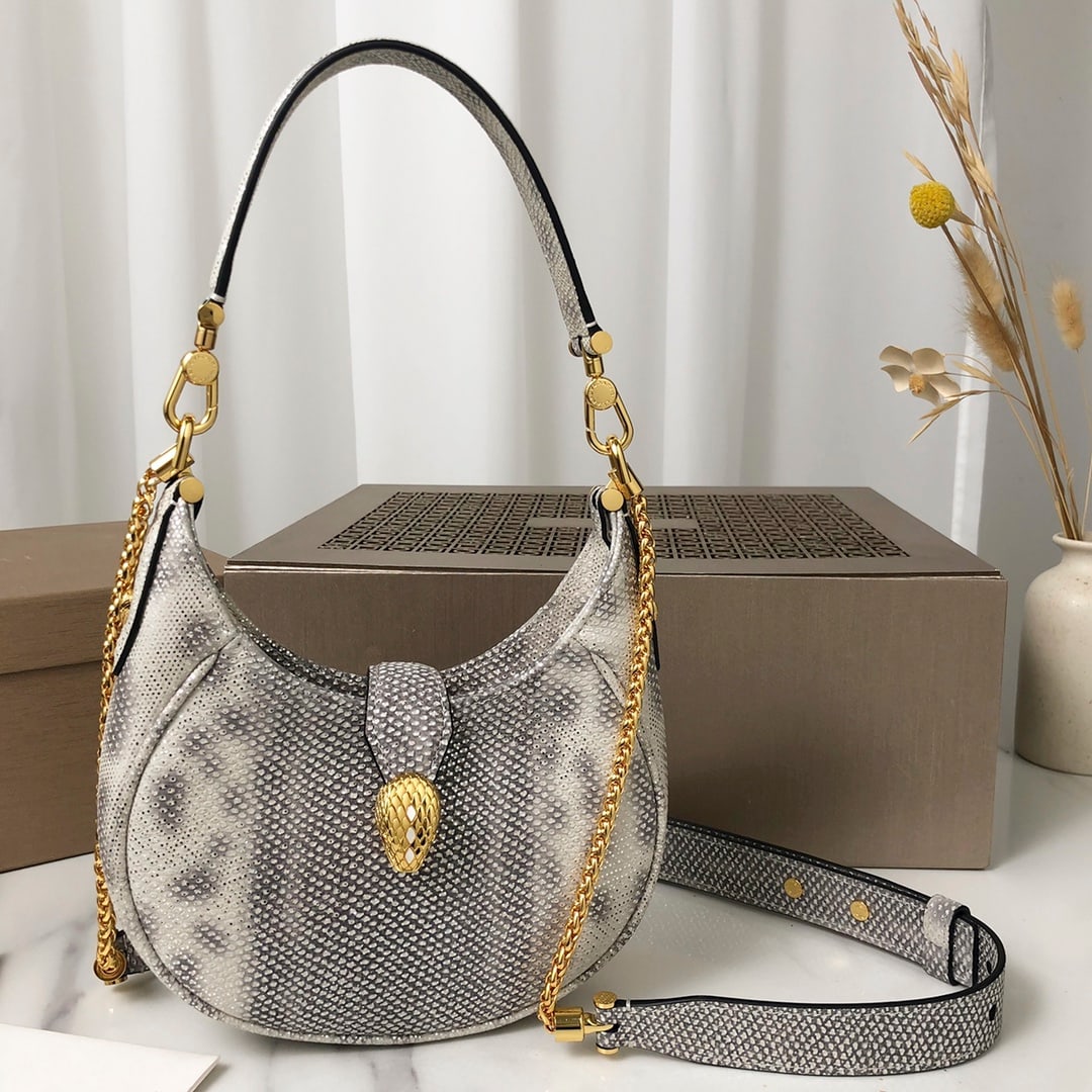 Bvlgari SERPENTI ELLIPSE: The Bvlgari Serpenti Ellipse small crossbody bag, with its unique shape, iconic details, and versatile charm, is crafted from moonshine silver calfskin and adorned with accessories. The captivating cl