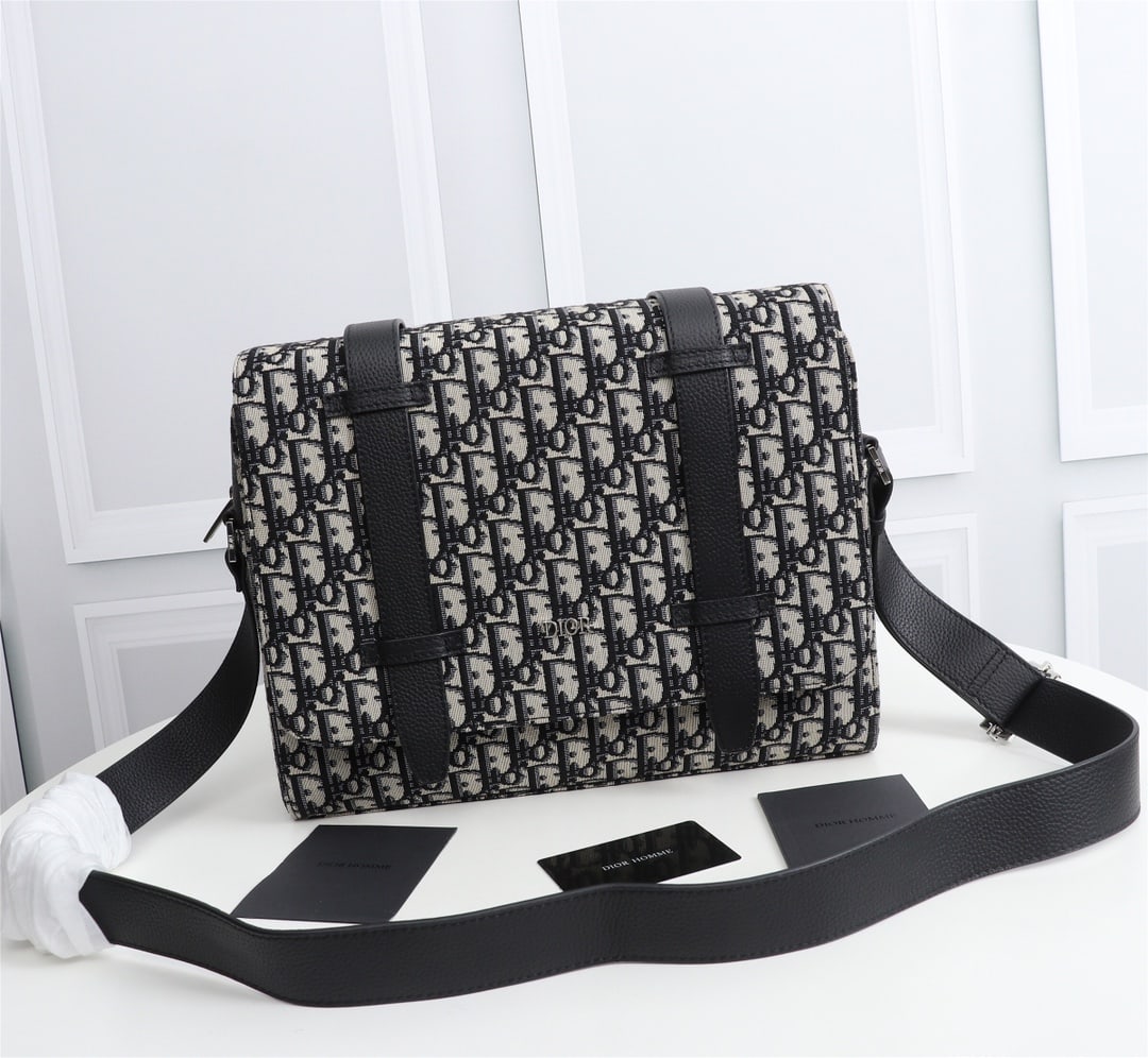 Christian Dior: Black Oblique print jacquard leather, black calfskin, front DIOR logo with embossed DIOR logo inside, adjustable leather shoulder strap, flap with zip closure, interior slip pocket. Can be worn over t