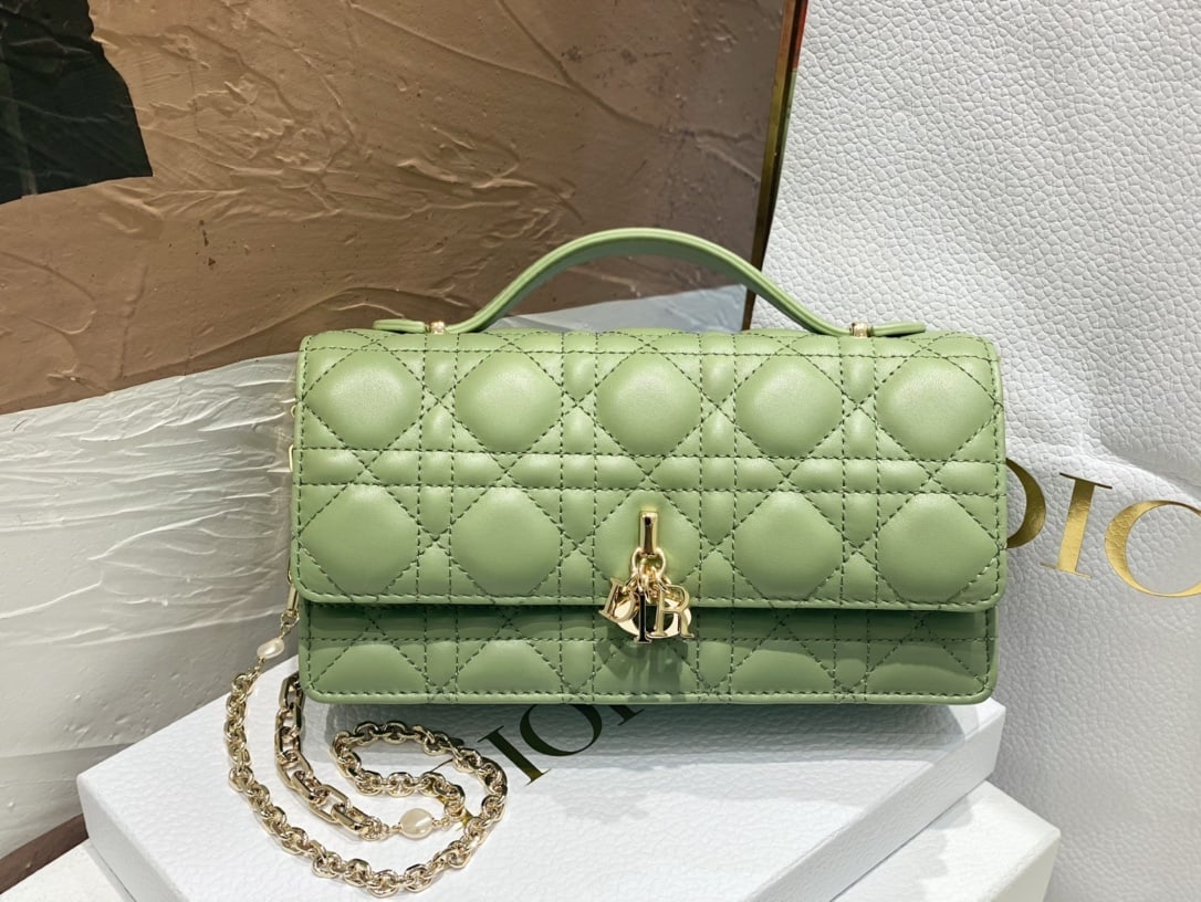 Christian Dior: The Lady Dior Pearl Clutch is an elegant and practical clutch bag that adds to the Lady Dior collection. Crafted from green lambskin leather with a cannage pattern, its flap design and DIOR charm elev