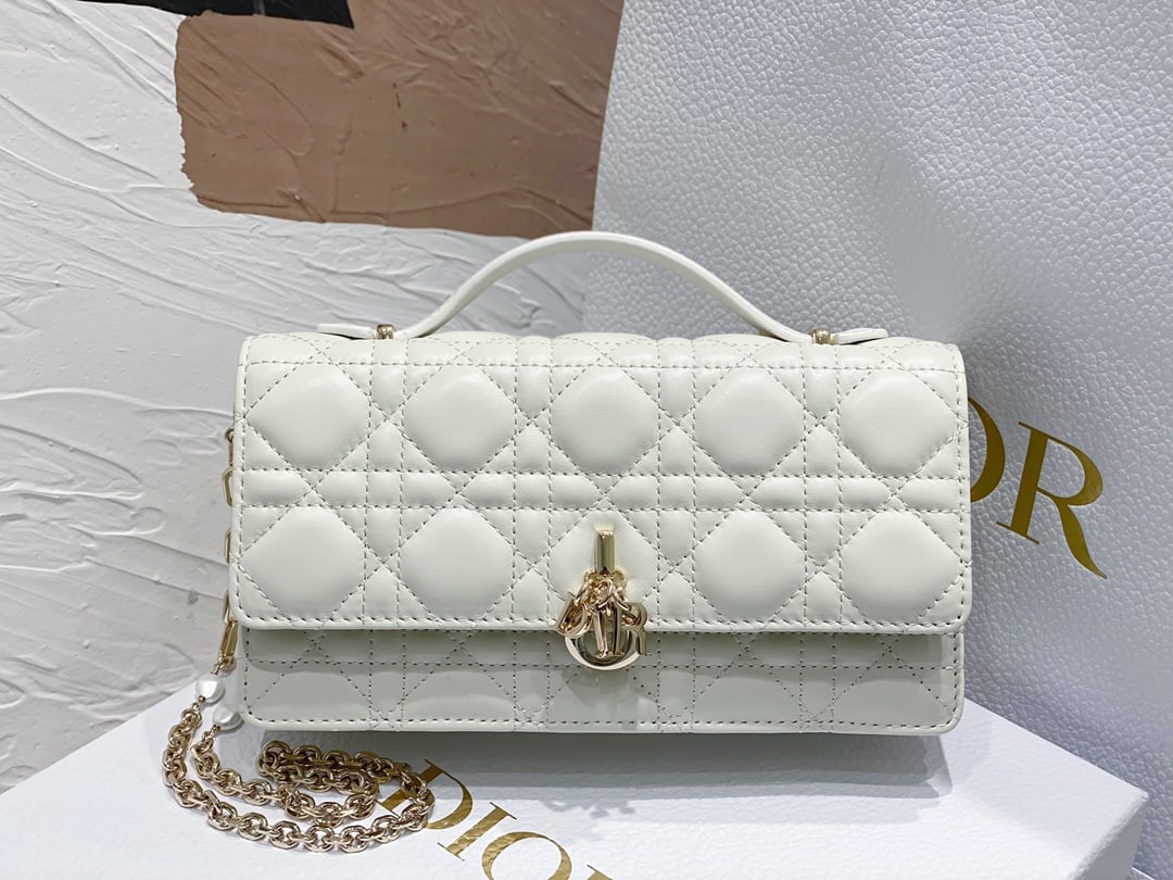 Christian Dior: The Lady Dior Pearl Clutch is an elegant and practical clutch bag that adds to the Lady Dior collection. Crafted from white lambskin leather with a cannage pattern, its flap design and DIOR charm elev
