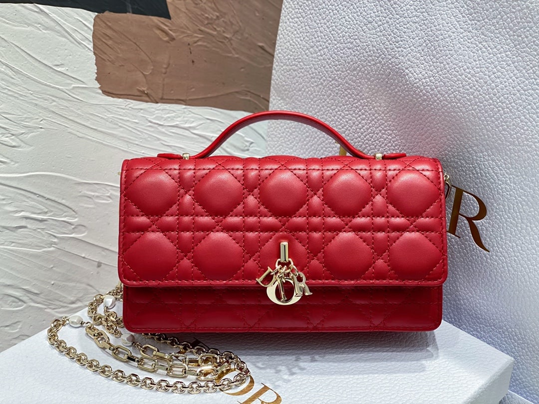 Christian Dior: The Lady Dior pearl clutch features a top handle, offering both elegance and practicality, enriching the Lady Dior collection. Crafted from red lambskin leather with a cannage pattern, the flap