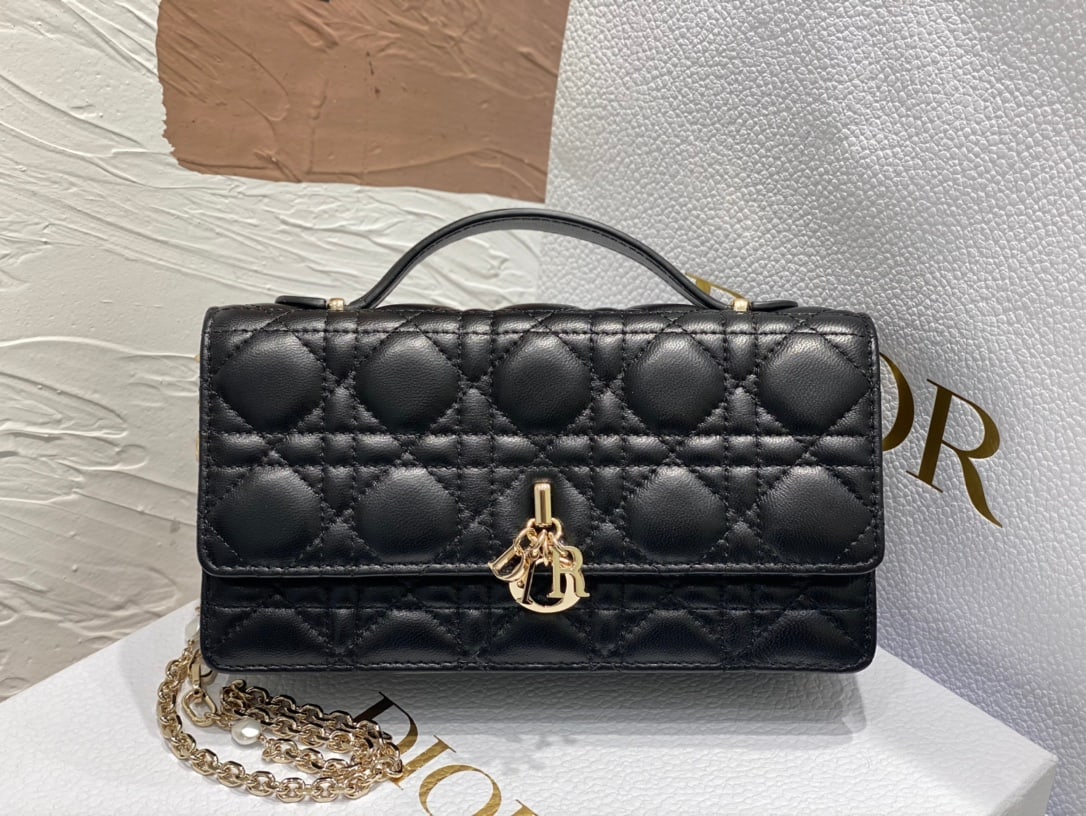 Christian Dior: The Lady Dior Pearl Clutch is an elegant and practical bag that adds to the Lady Dior collection. Crafted from black lambskin leather with a cannage pattern, its flap design and DIOR charm elevate