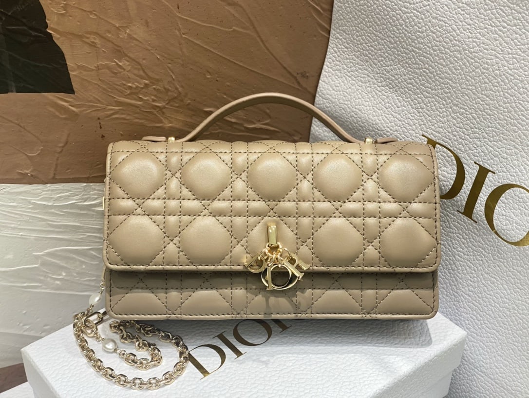 Christian Dior: The Lady Dior Pearl Clutch is an elegant and practical bag that adds to the Lady Dior collection. Crafted from natural-colored lambskin leather with a cannage pattern, its flap design and DIOR charm e