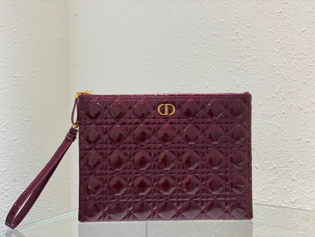 Christian Dior: The Dior Caro everyday clutch is an elegant and practical piece. Crafted from burgundy patent calfskin leather, it features the iconic cannage stitching and a CD logo on the front. The large size can 