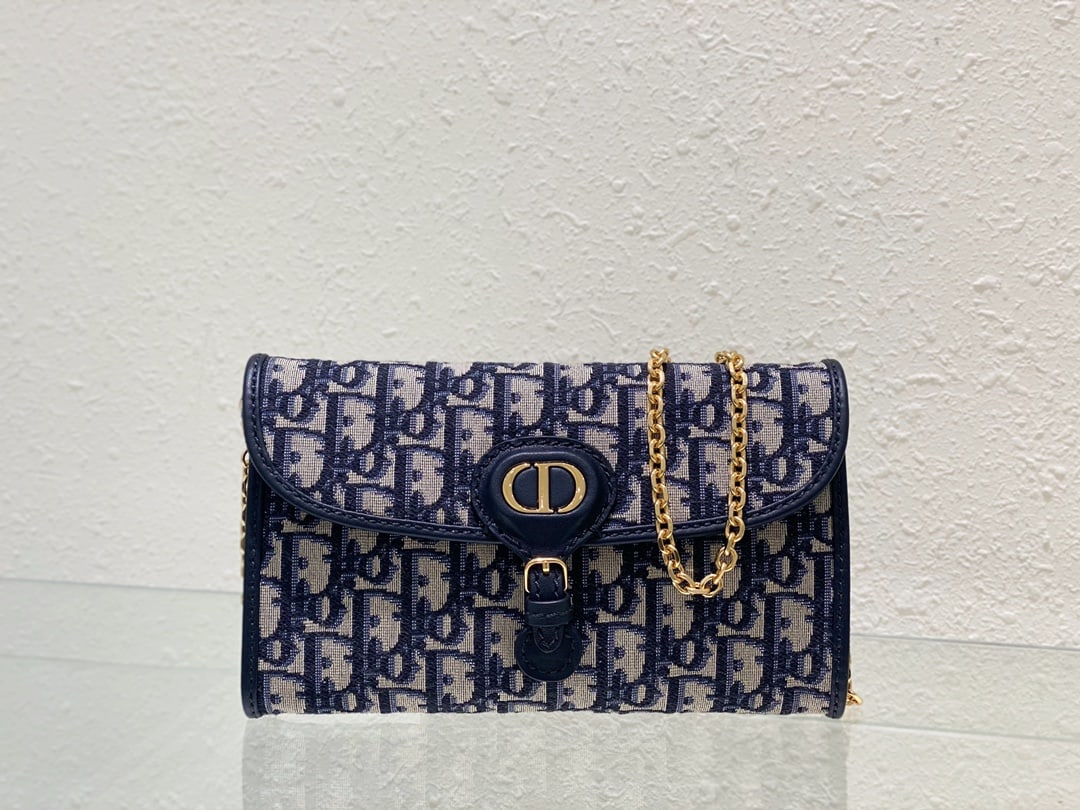 Christian Dior: The DIOR BOBBY EAST-WEST Chain Handbag in Blue Oblique Print is a stylish and elegant piece from the Summer 2023 collection. Crafted from blue Oblique print fabric, the bag features a sophisticated