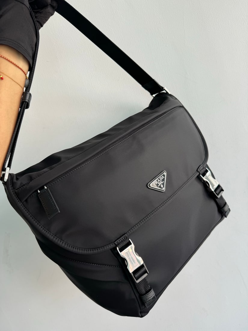 PRADA messenger bag: This messenger bag is made from Re-Nylon, a recycled nylon yarn material. It features a flap and snap closure, three exterior zip pockets, an interior zip pocket, and a patch pocket. It boasts a