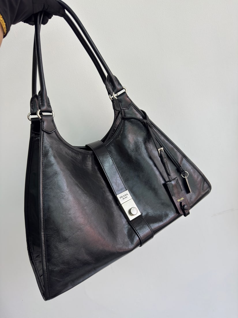PRADA: This runway piece is made of imported oil-waxed leather and top-quality hardware. It features a snap closure on the front, a large capacity, and can be carried by hand or over the shoulder. It has a