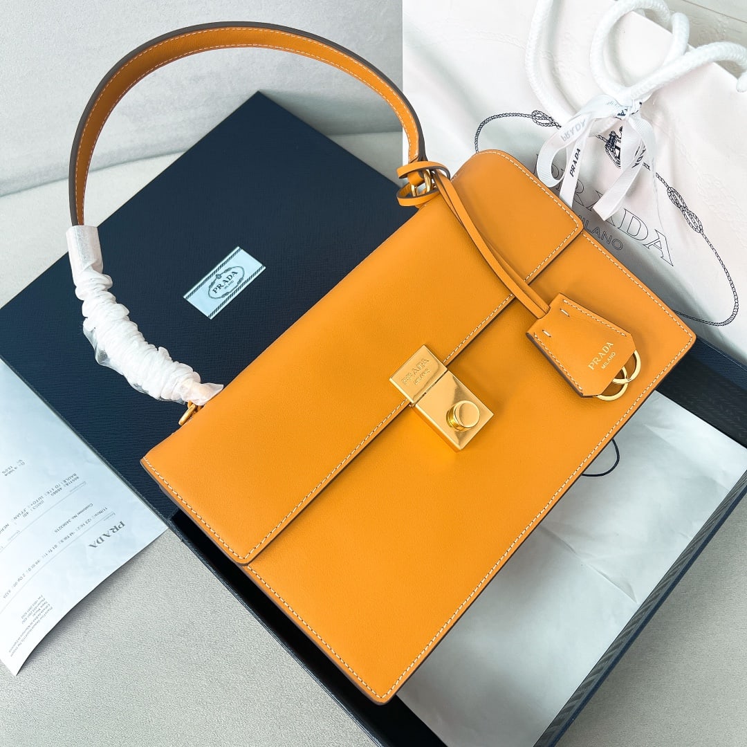 PRADA leather handbag: This calfskin leather handbag is inspired by the structured, minimalist, and formal briefcase, reinterpreting the classic office silhouette with attitude. Refined and soft details infuse the classic