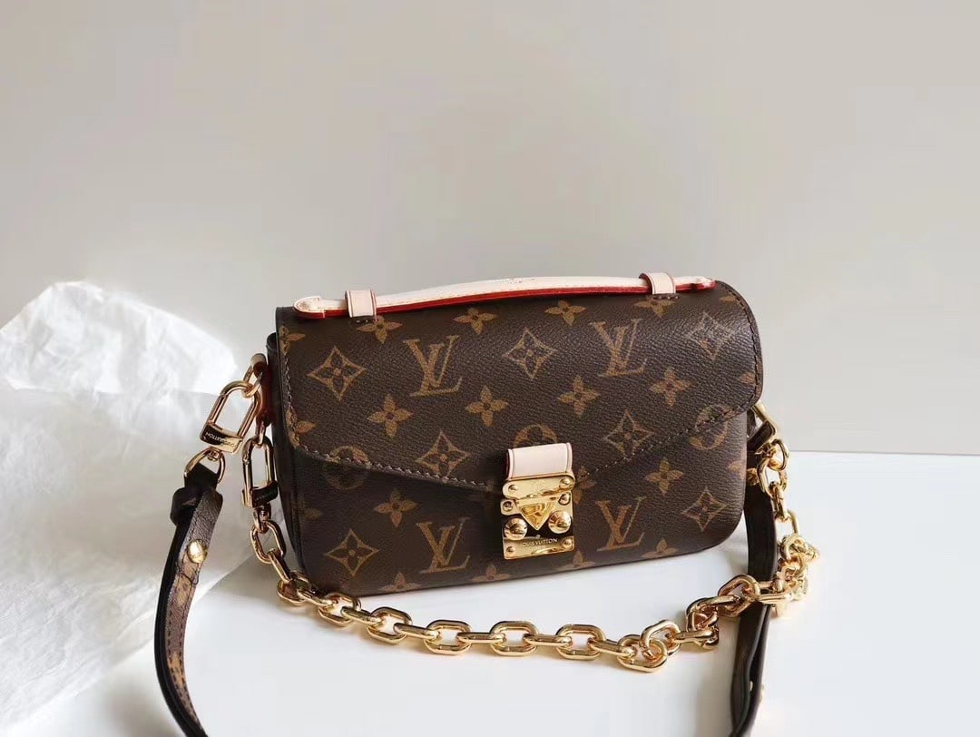 LV East West MEtis: East West MEtis. A compact bag crafted from the brand's Monogram canvas, featuring a chic S-lock closure and a stylish top handle. The polished surface boasts a gleaming shine. Versatile and