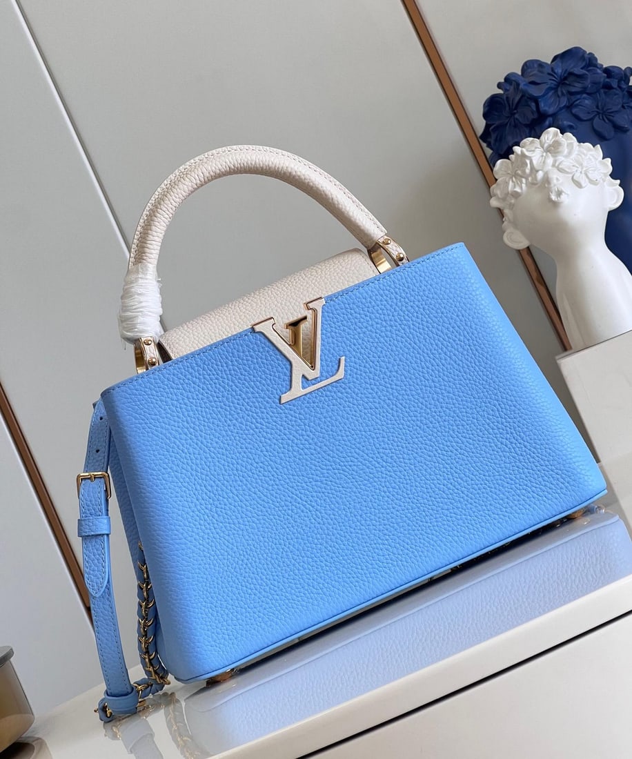 LV Capucines MM: The blue and white chain medium-sized Capucines MM handbag features vibrant colors on the LV monogram and woven chain, contrasting with the understated elegance of the Taurillon leather body.