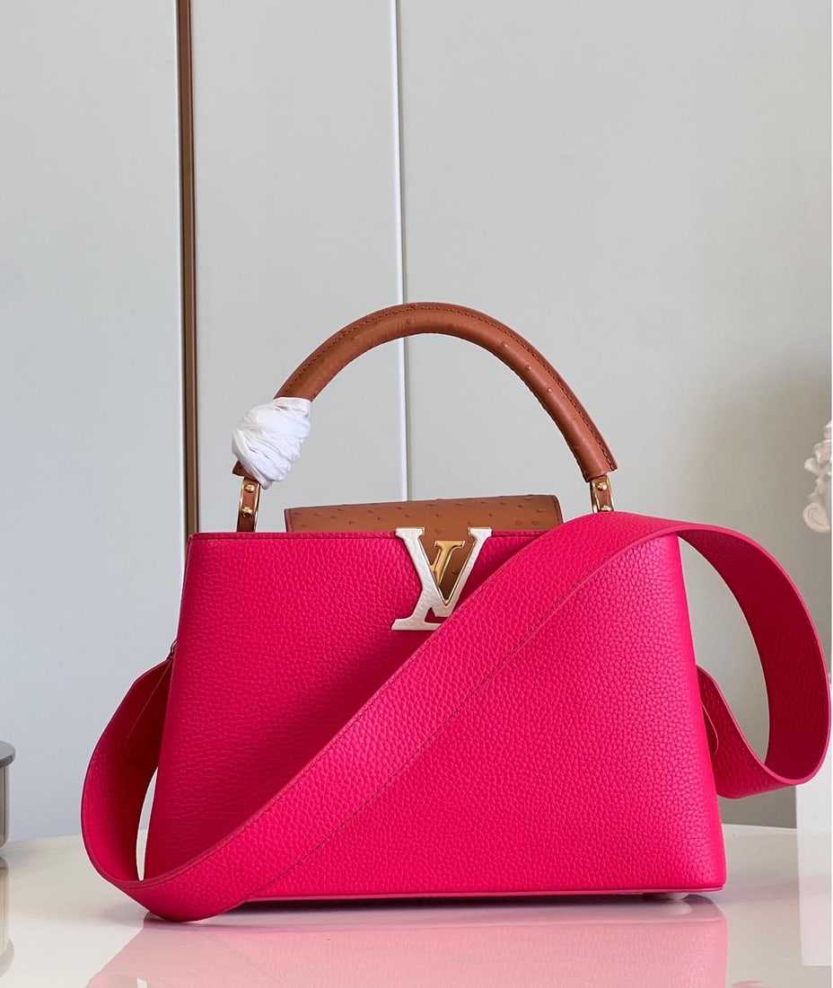 LV Capucines MM: The medium-sized Capucines MM handbag in fuchsia is crafted from Taurillon leather, featuring a sleek silhouette. The flap, handles, and LV logo are wrapped in ostrich leather. The flap can be opened