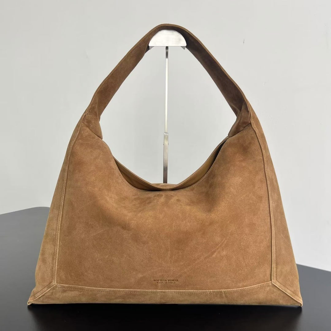 Bottega Veneta Hop: The Bottega Veneta Large Suede Hop Handbag features a one-piece molded suede design that replaces the woven exterior for a more minimalist and stylish look. The bag is soft and comfortable, with a dou