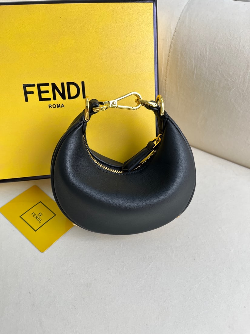 FENDI Praphy: This small black FENDI Praphy underarm bag features a crescent shape and a classic large metal logo at the bottom. The bag's silhouette hugs the body's lines, creating a stylish look when worn under