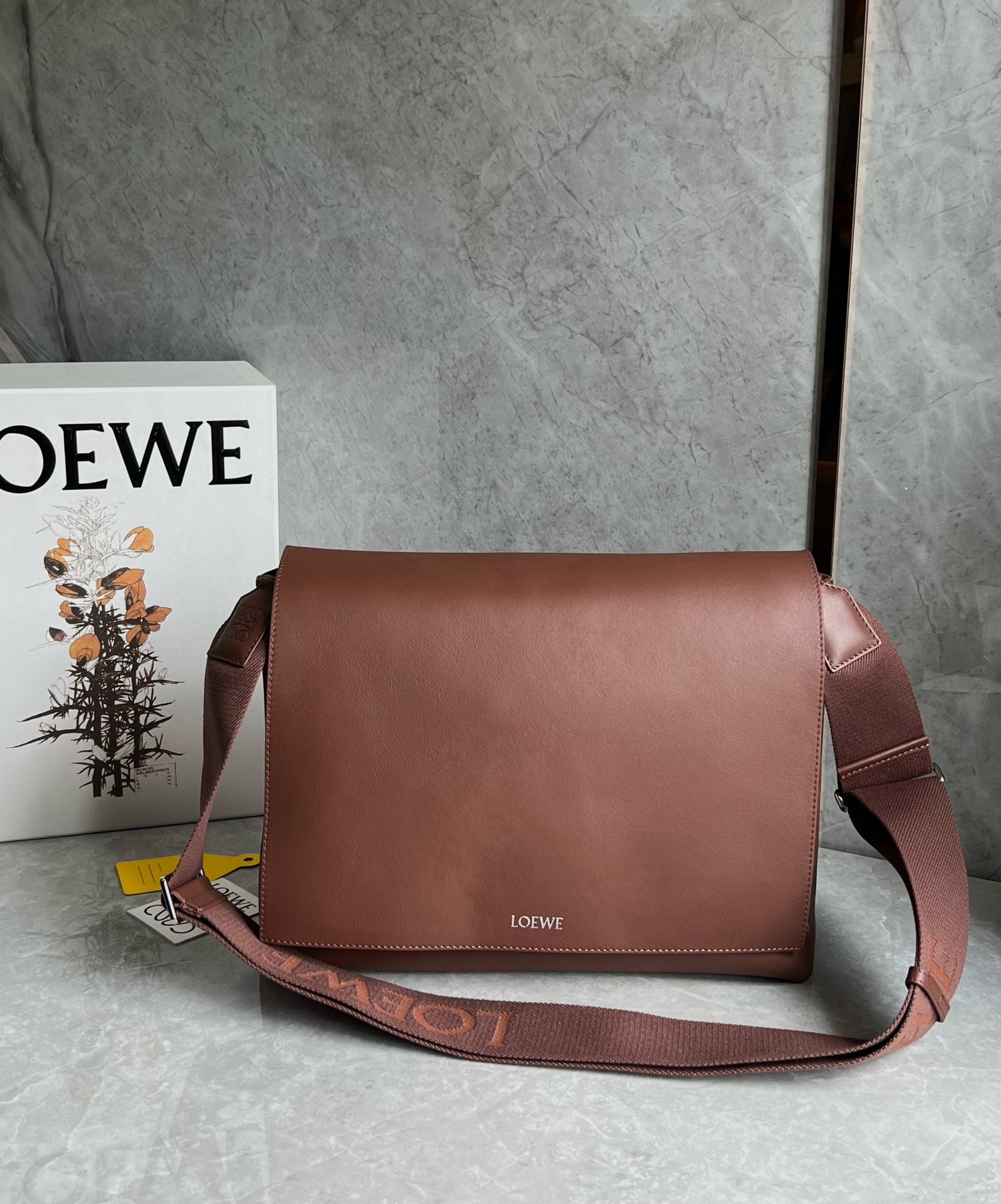 LOEWE: This LOEWE Flamenco satchel messenger bag is crafted from supple calfskin in glossy finish. It reimagines the classic Flamenco bag as a practical crossbody bag with a drawstring closure and the