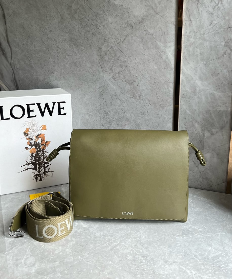 LOEWE: This LOEWE Flamenco satchel messenger bag is crafted from supple calfskin in glossy finish. It reimagines the classic Flamenco bag as a practical crossbody bag with a drawstring closure and the