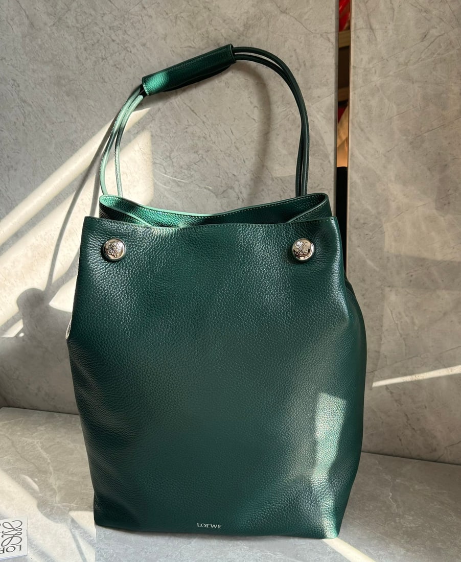 LOEWE: The LOEWE Pebble hobo is a minimalist vertical bag featuring the iconic Anagram Pebble design. Crafted from supple grained calfskin, it includes a leather shoulder strap with a shoulder strap, a
