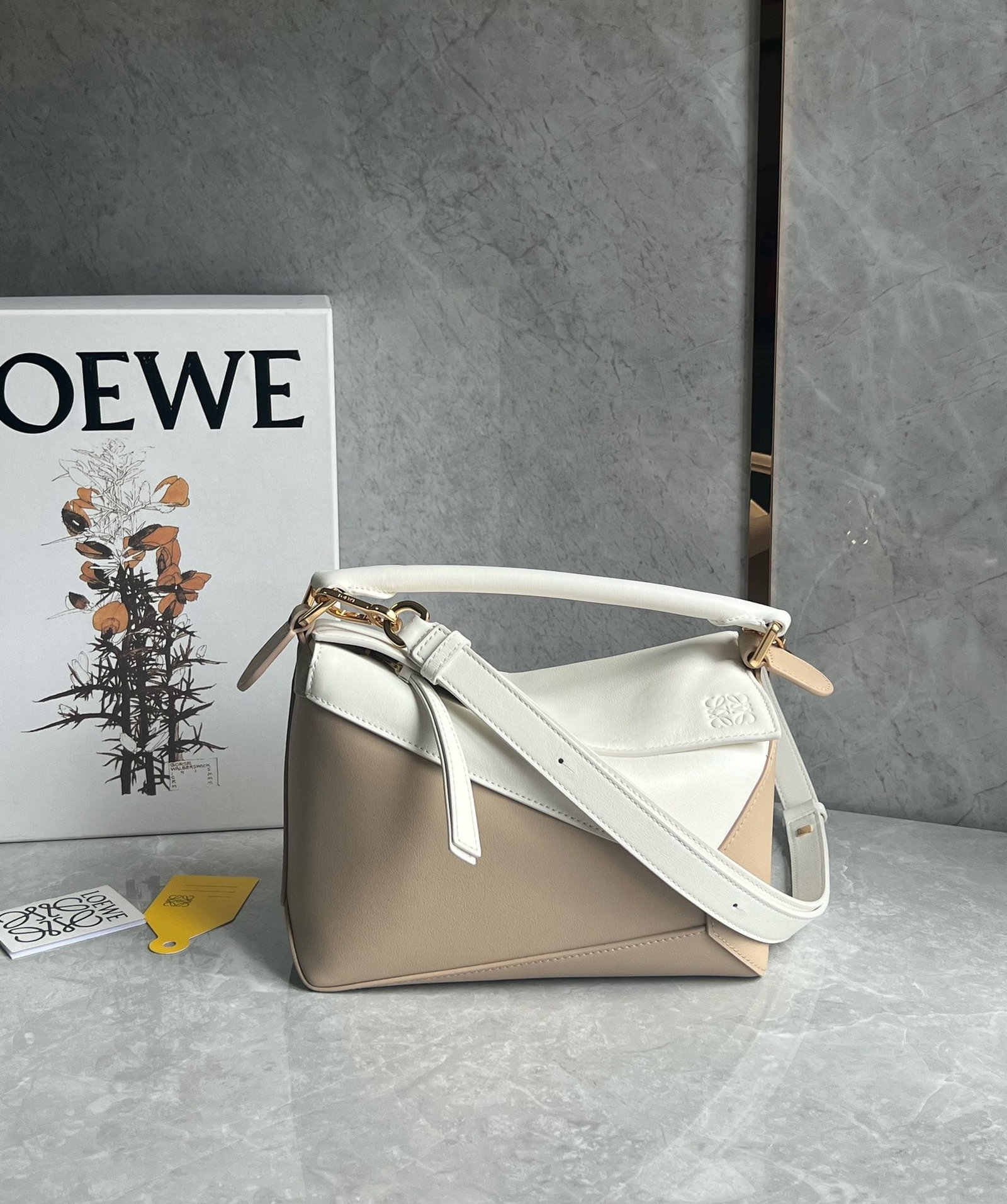 LOEWE: The LOEWE Puzzle bag, in a creamy white color-blocked design, is made of calfskin. It's lightweight yet surprisingly spacious, practical, versatile, and convenient for travel. Small size: 24 x 16 x