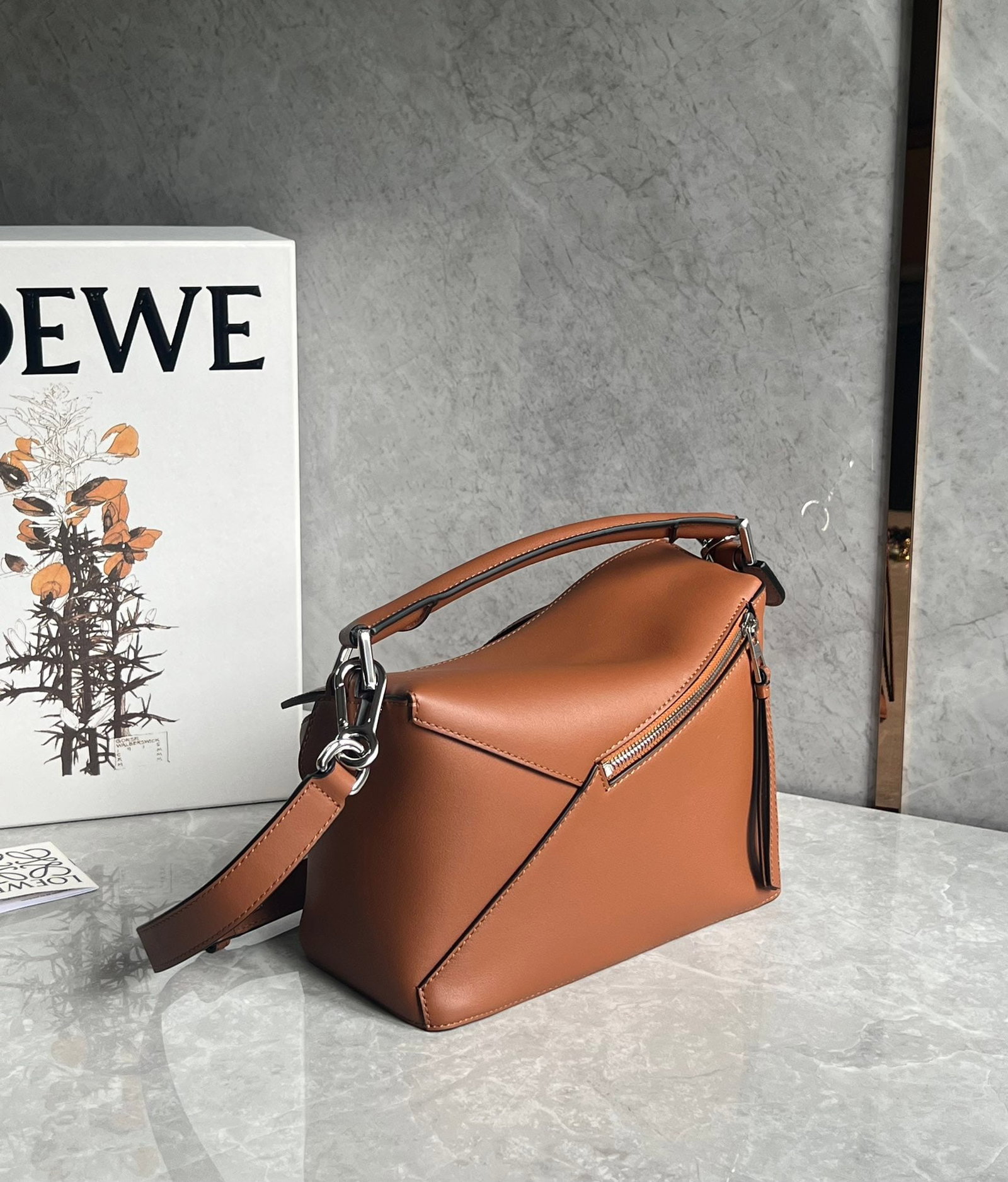 LOEWE: The LOEWE Puzzle in caramel brown is made of calfskin, with a sand-colored patchwork design throughout. It's lightweight yet has a surprisingly large capacity, making it practical, versatile, and