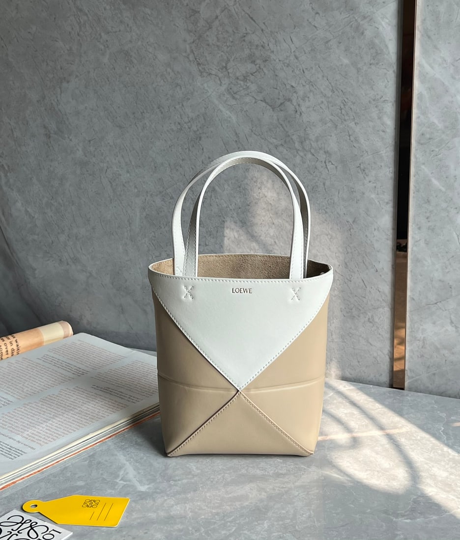 LOEWE: The LOEWE Puzzle Fold Tote bag is crafted entirely from Nappa calfskin. Inspired by origami, the Puzzle Fold Tote boasts clean lines and an understated elegance. It's incredibly soft and spacious, wit